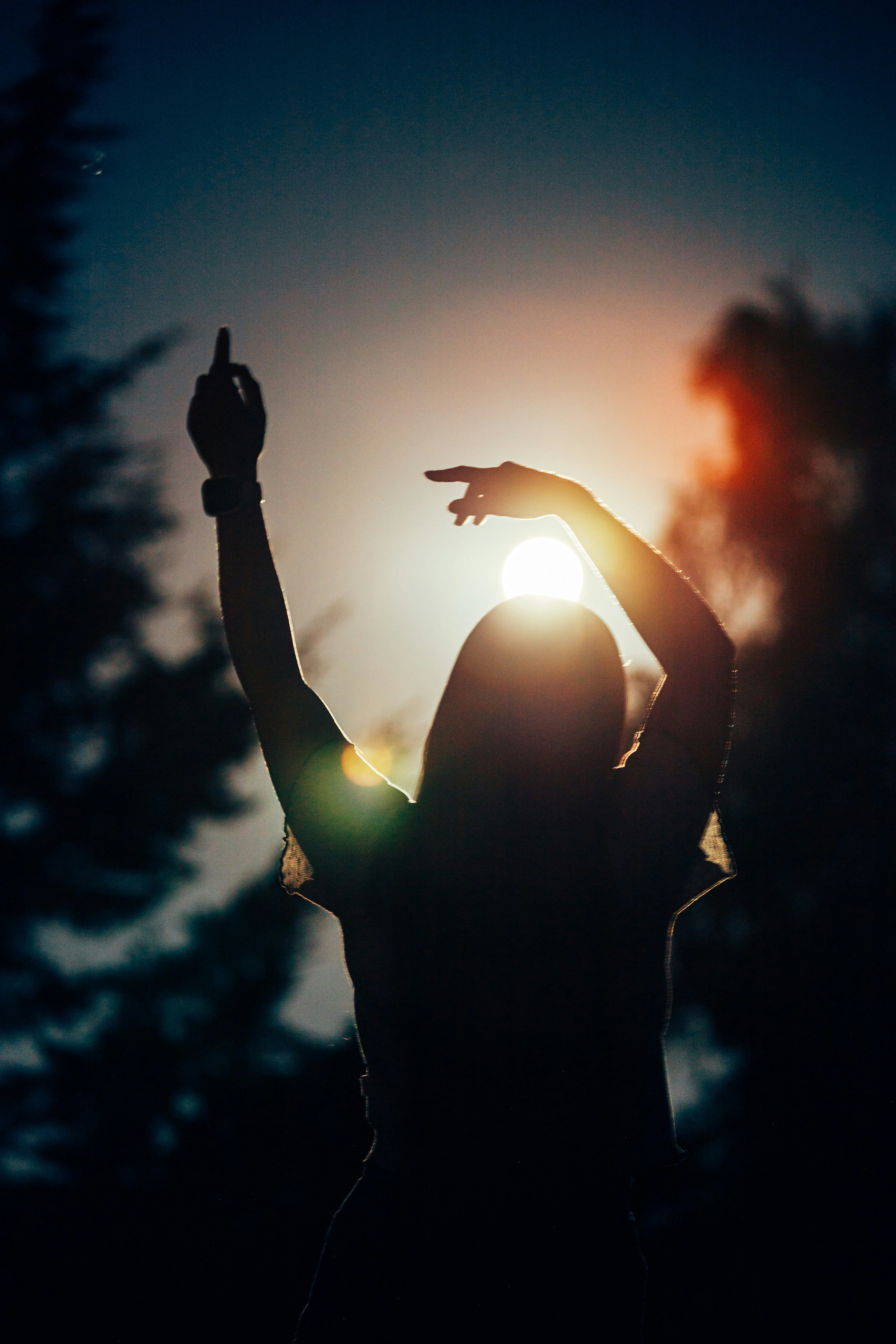 silhouetted woman dancing with sun setting