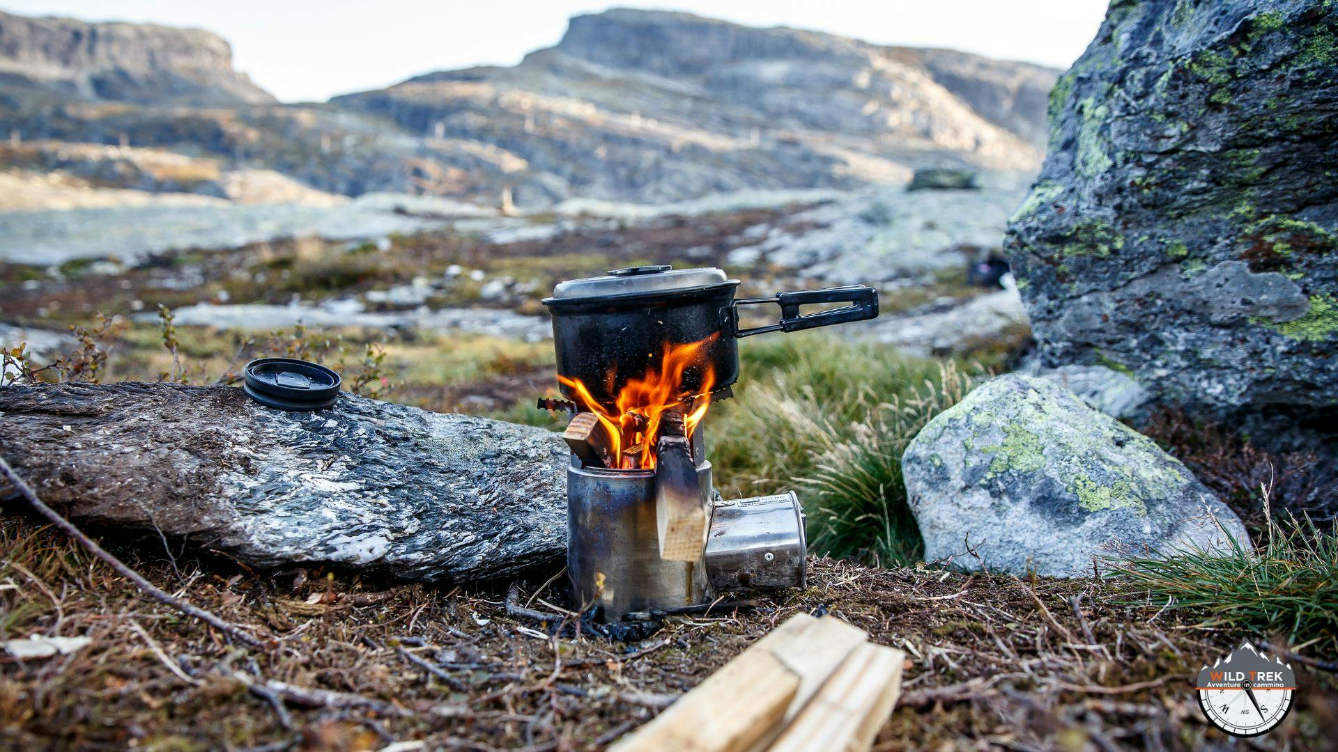 Fornello da campeggio con pentola sul fuoco in ambiente montano