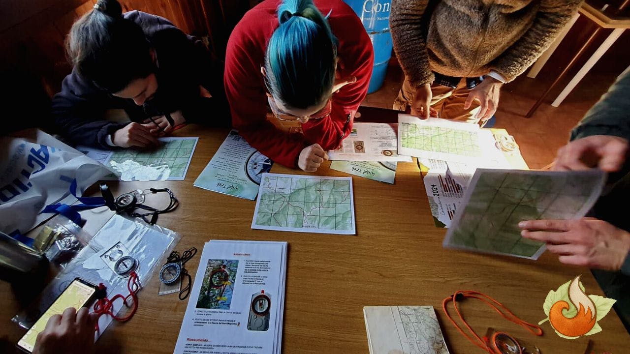 Gruppo di partecipanti al corso di escursionismo mentre leggono una cartina in un bivacco