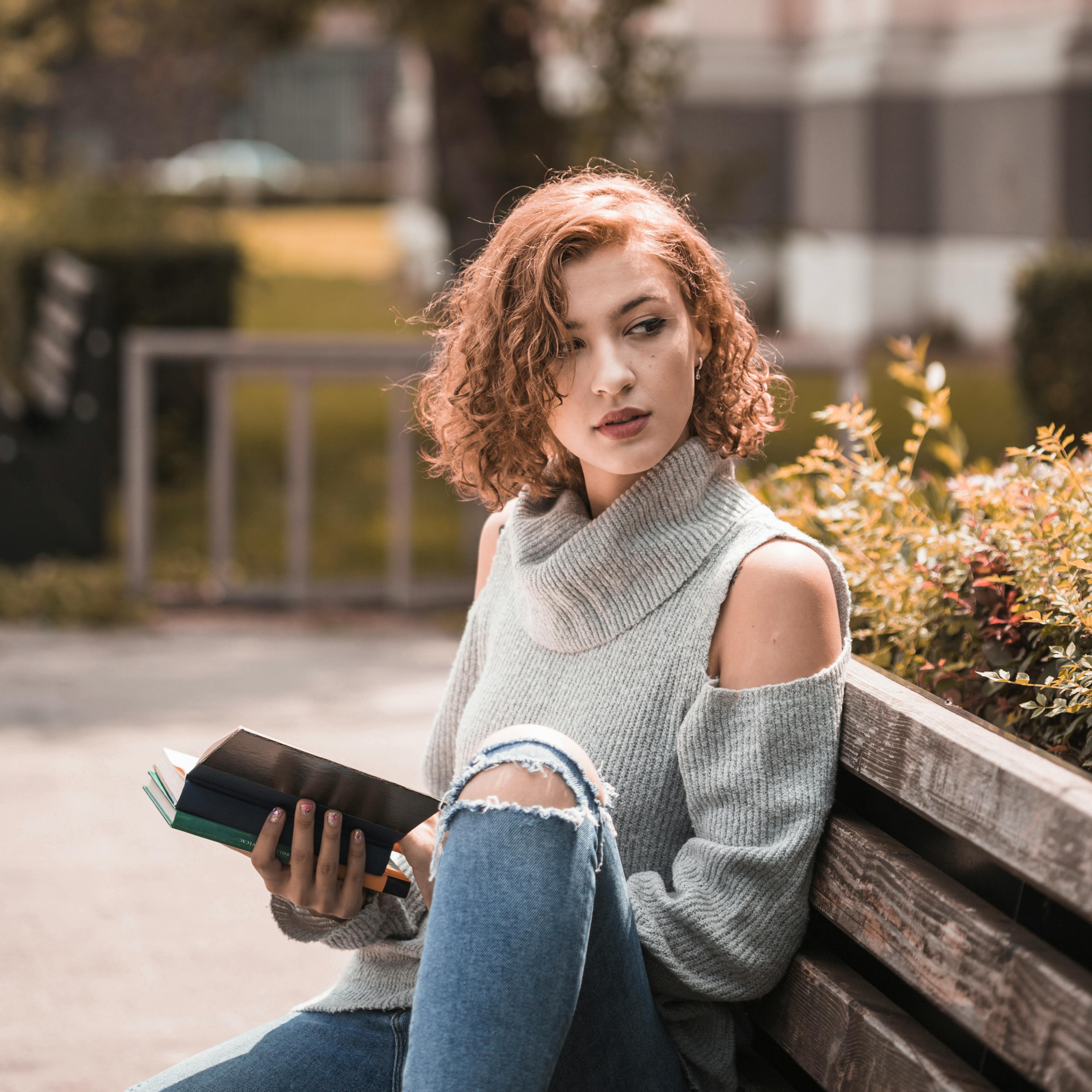 young-woman-sitting-on-a-bench-with-books-student-studying