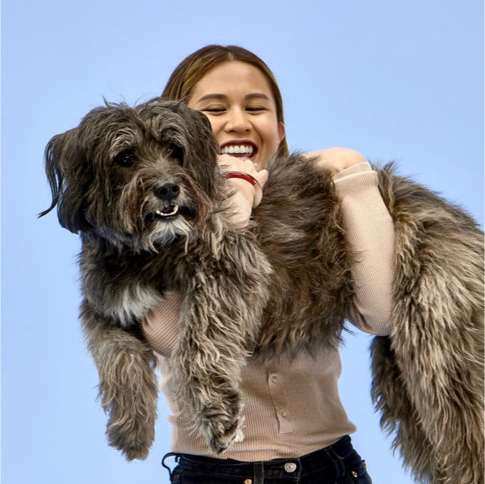 Laughing woman carrying a large dog in her arms