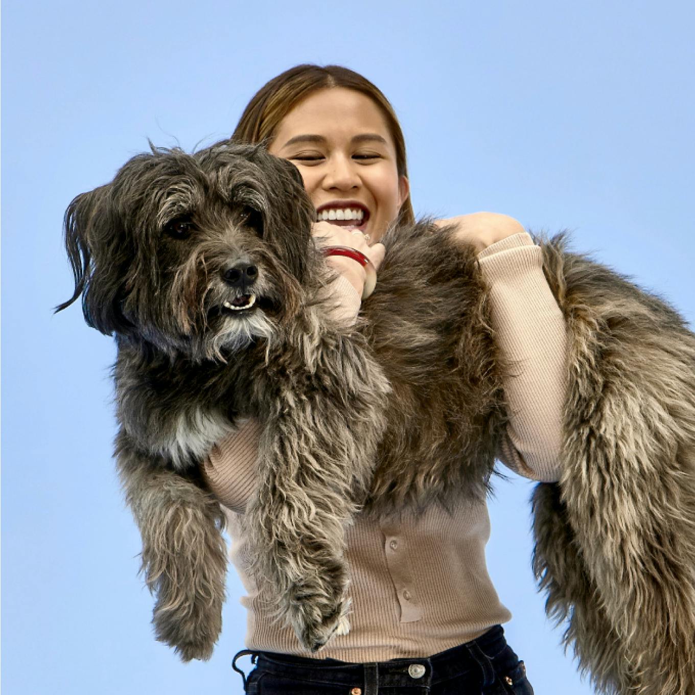Laughing woman carrying a dog in her arms