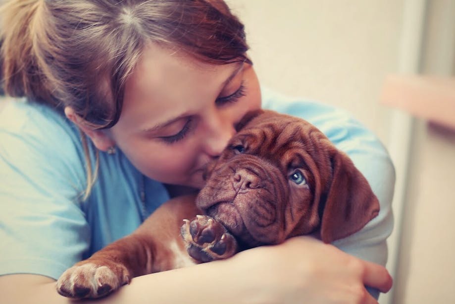 Woman hugging and kissing her puppy