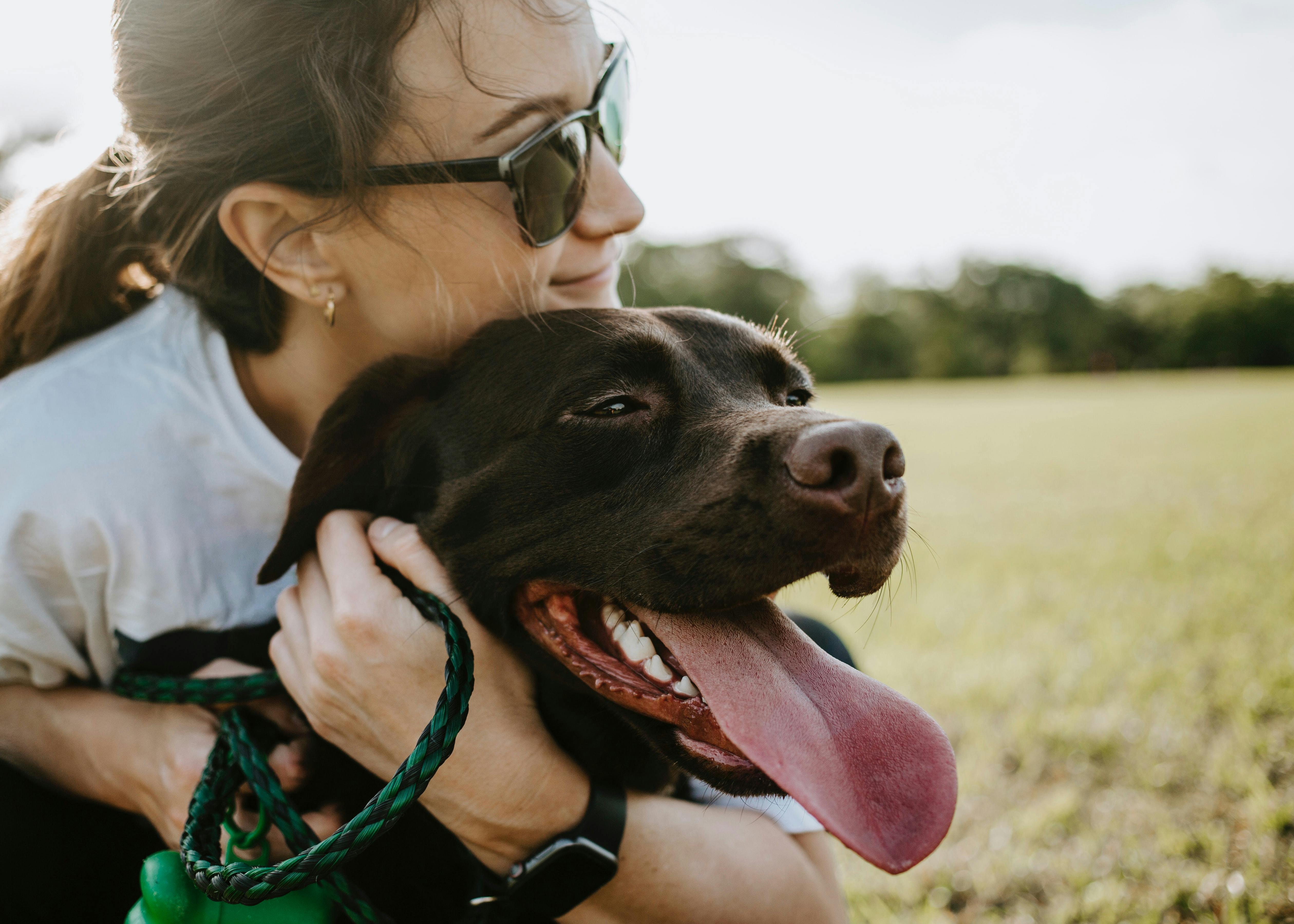 Woman hugging dog outside.