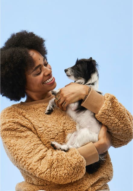 A smiling woman holding a puppy in her arm