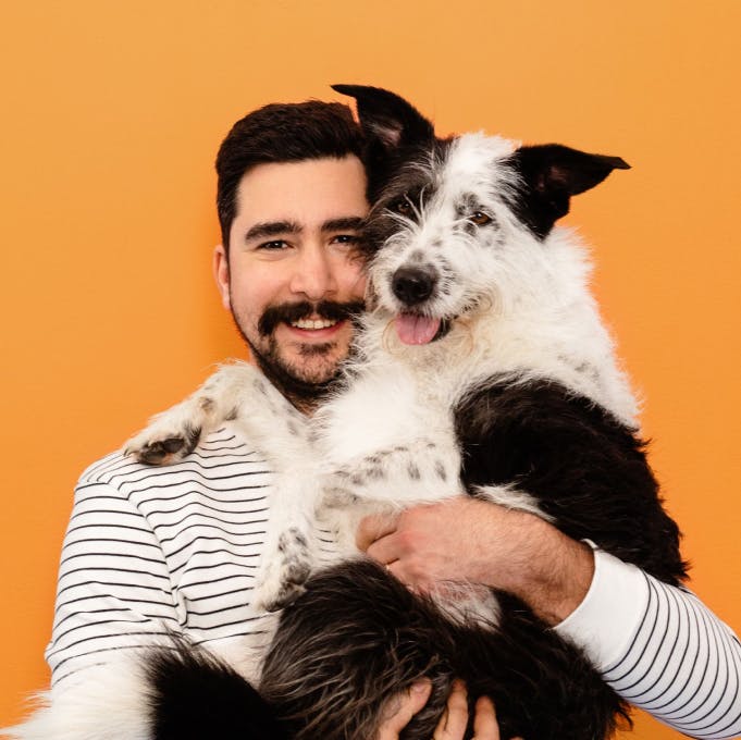 A man holding a black and white dog in his arms