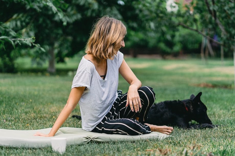 Woman sitting on blanket outside beside her black dog