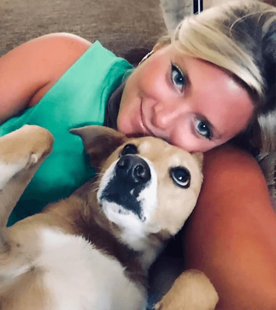 A lady and her dog lying with their back to the bed