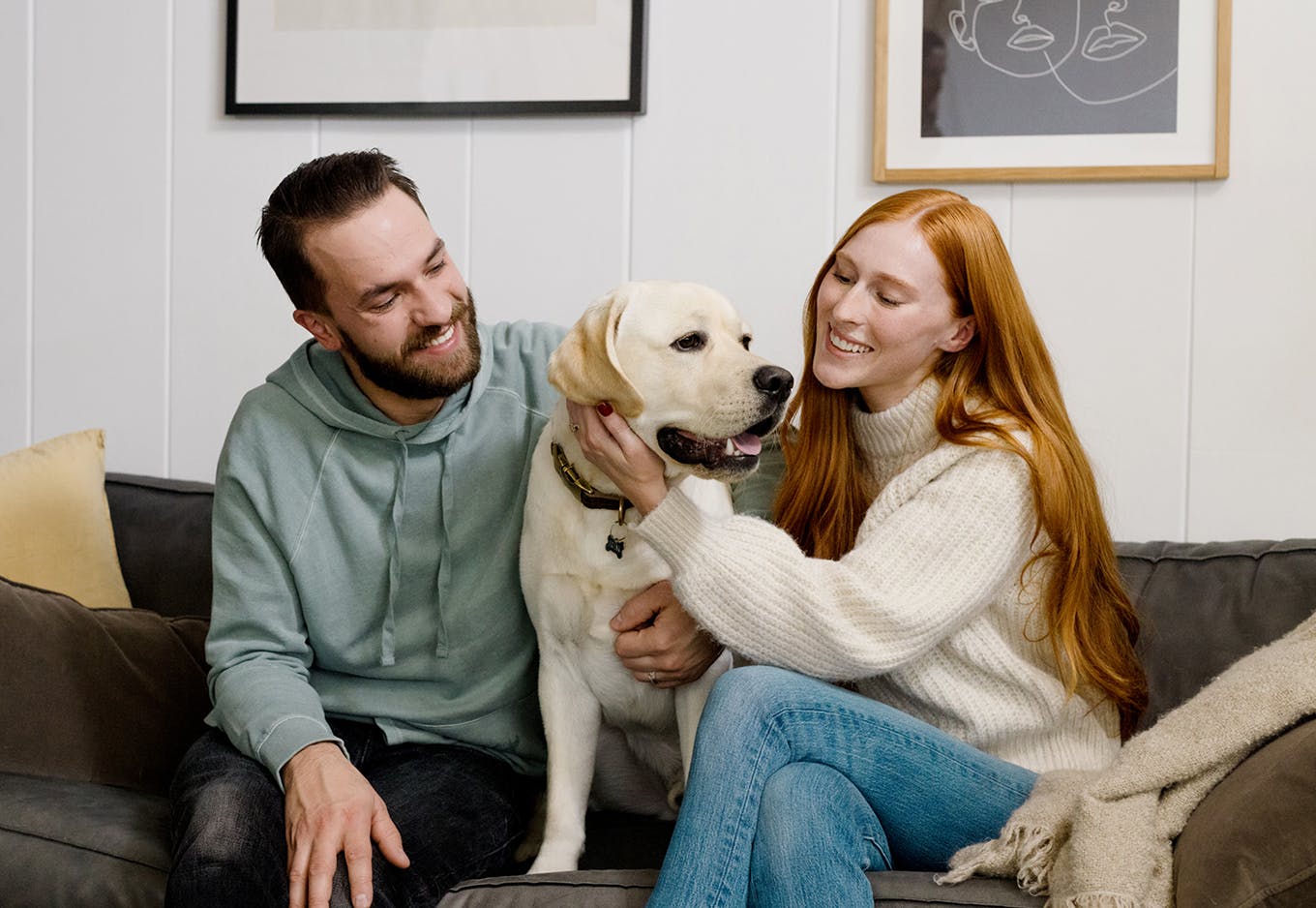 A man and a woman sitting on the couch with their dog