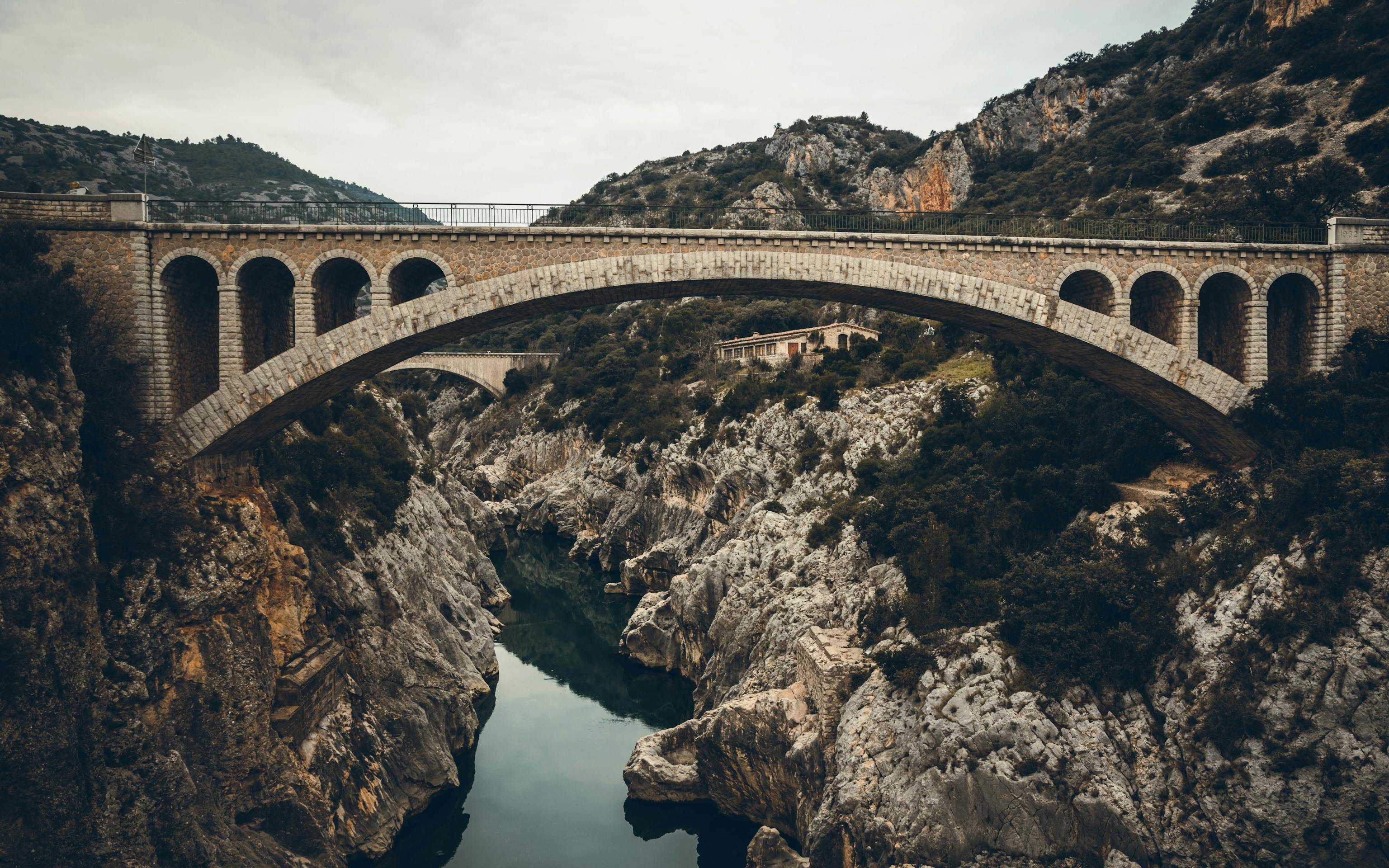A stone bridge over a deep ravine with a river flowing through it