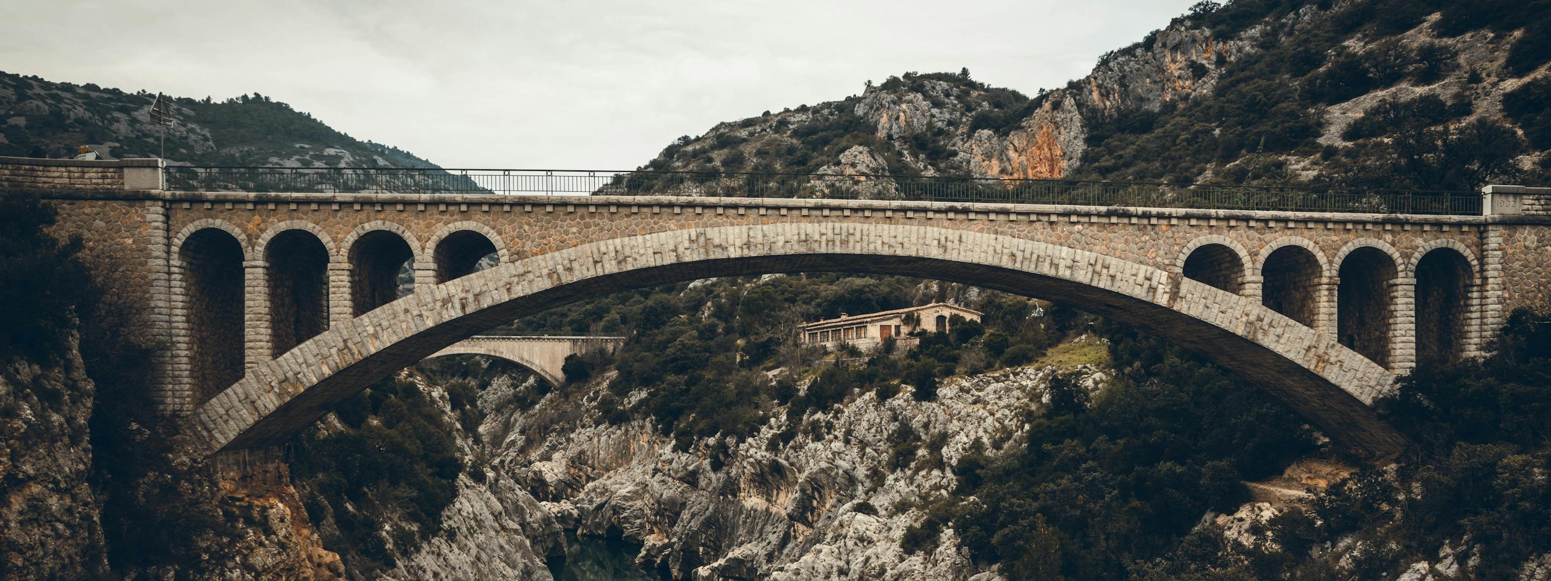 A stone bridge over a deep ravine with a river flowing through it