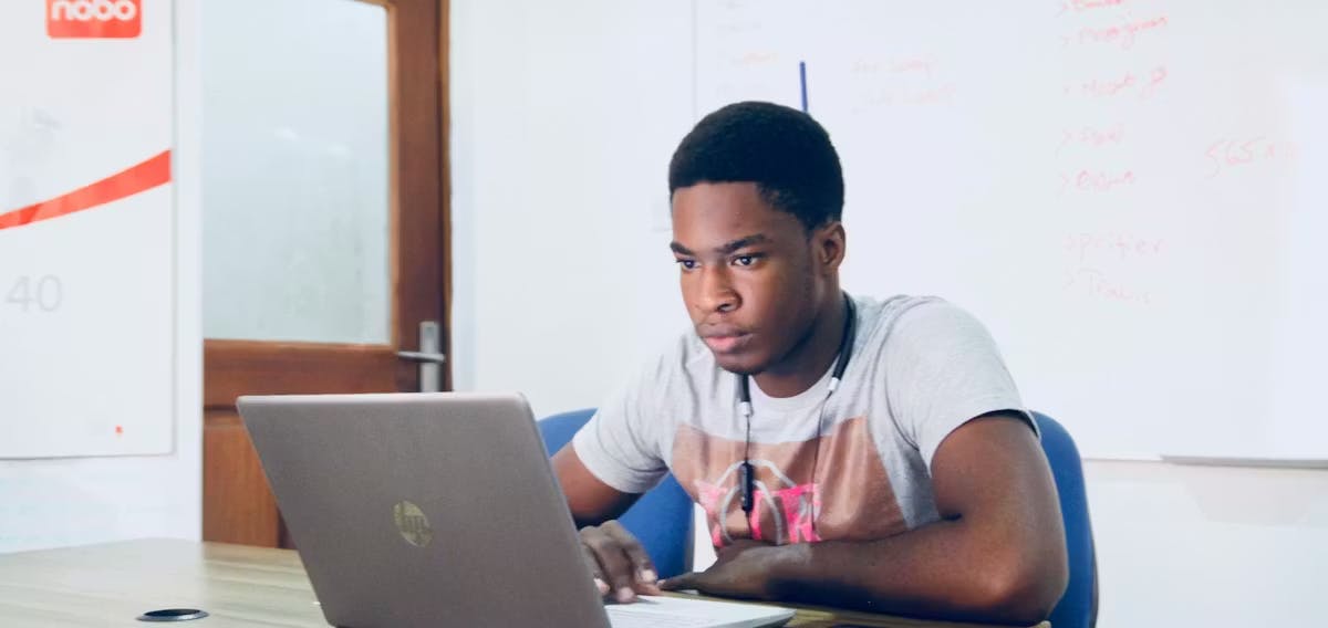 A young man focused on his laptop in an office setting, working on technical improvements like website speed optimization to ensure a high-quality mobile responsive website experience.