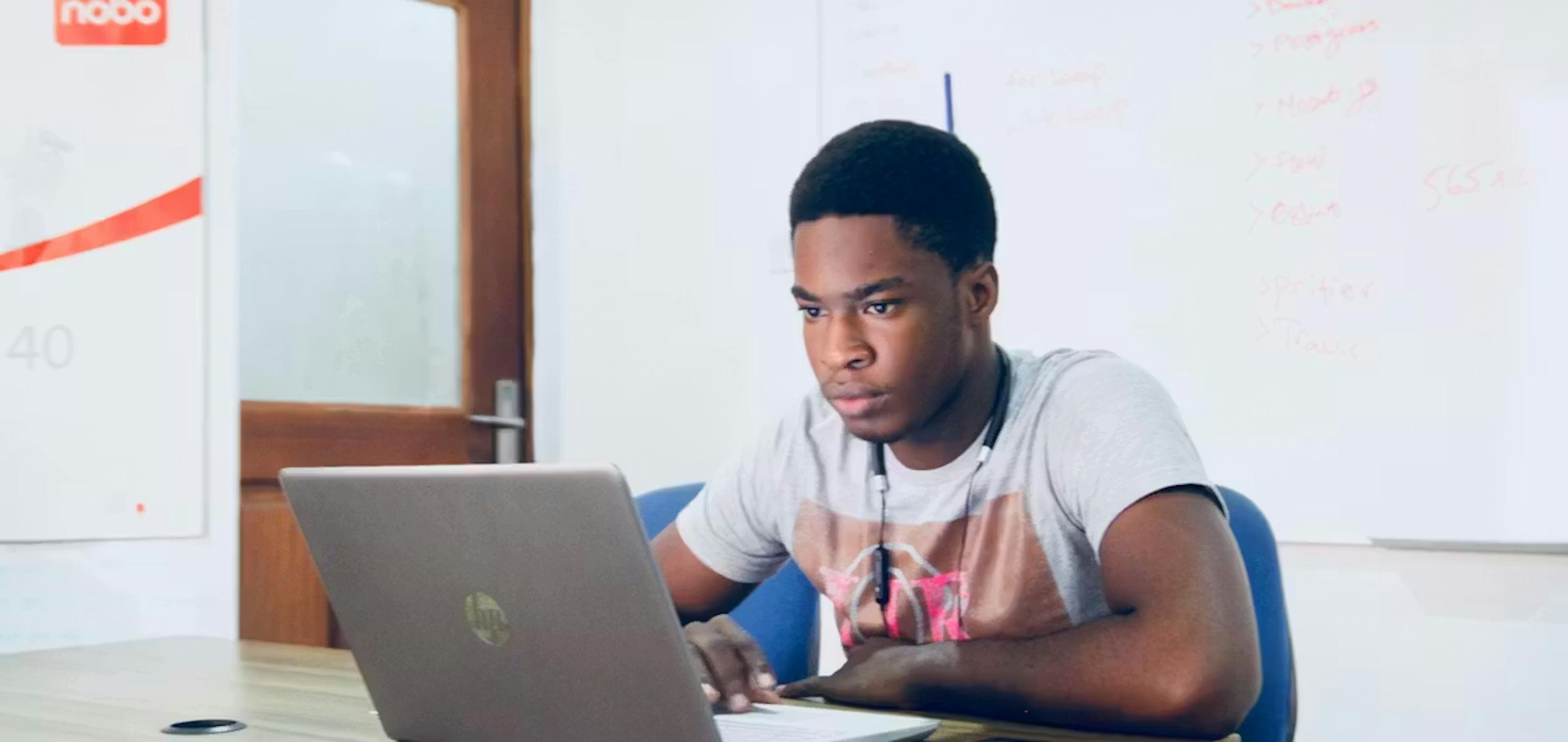 A young man focused on his laptop in an office setting, working on technical improvements like website speed optimization to ensure a high-quality mobile responsive website experience.