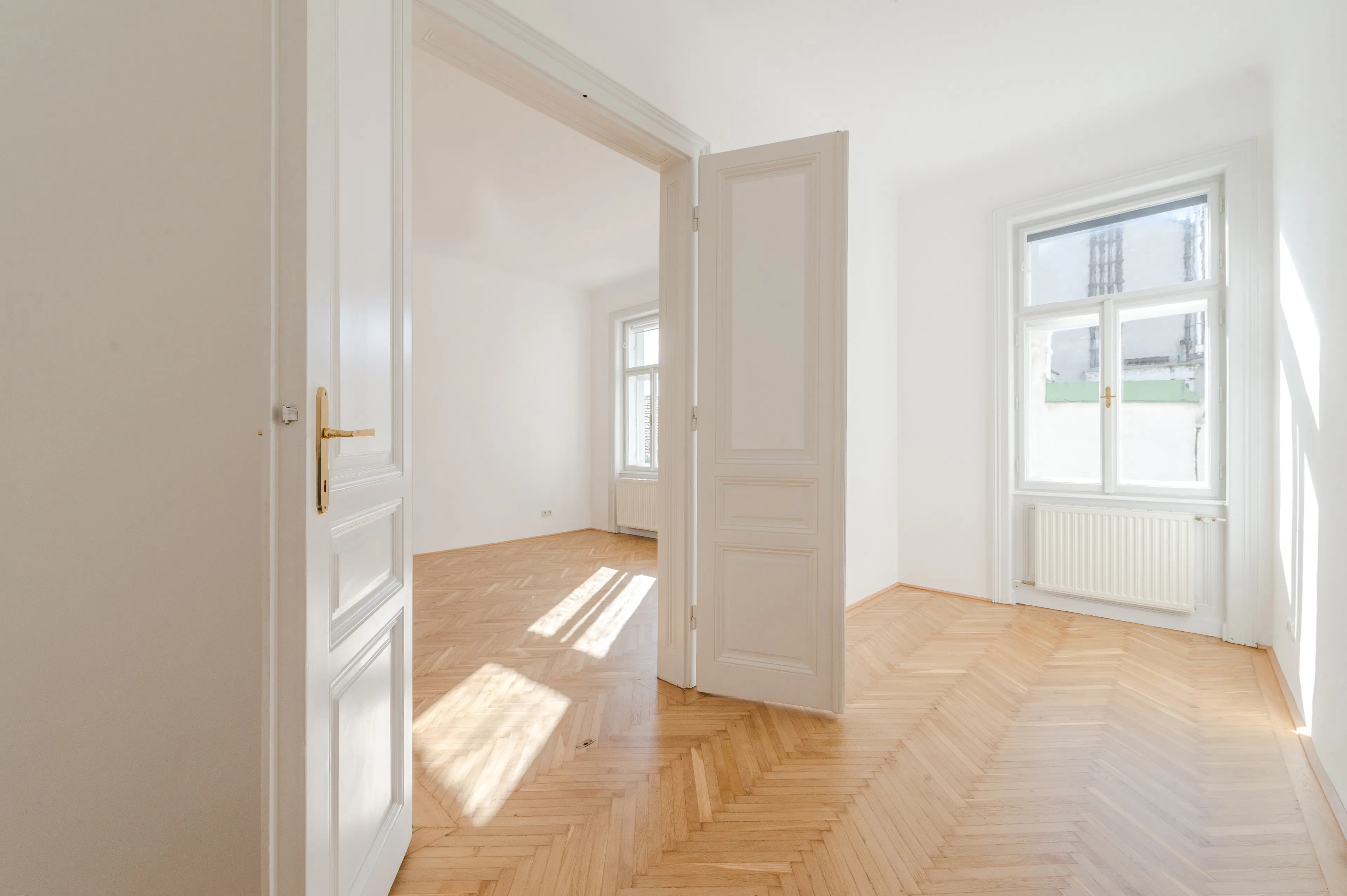 Heller Altbauraum mit Holzparkett und Flügeltüren