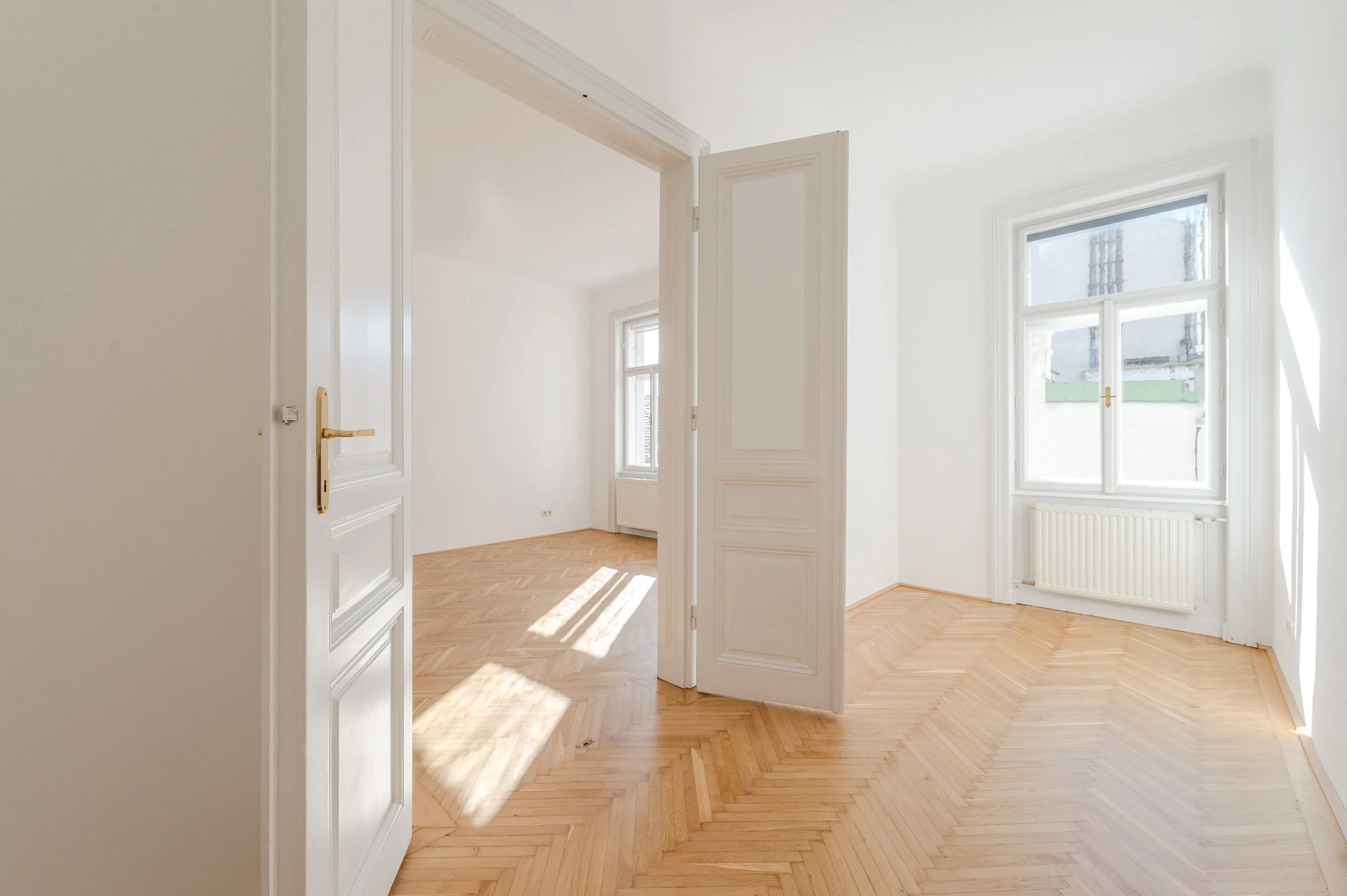 Heller Altbauraum mit Holzparkett und Flügeltüren