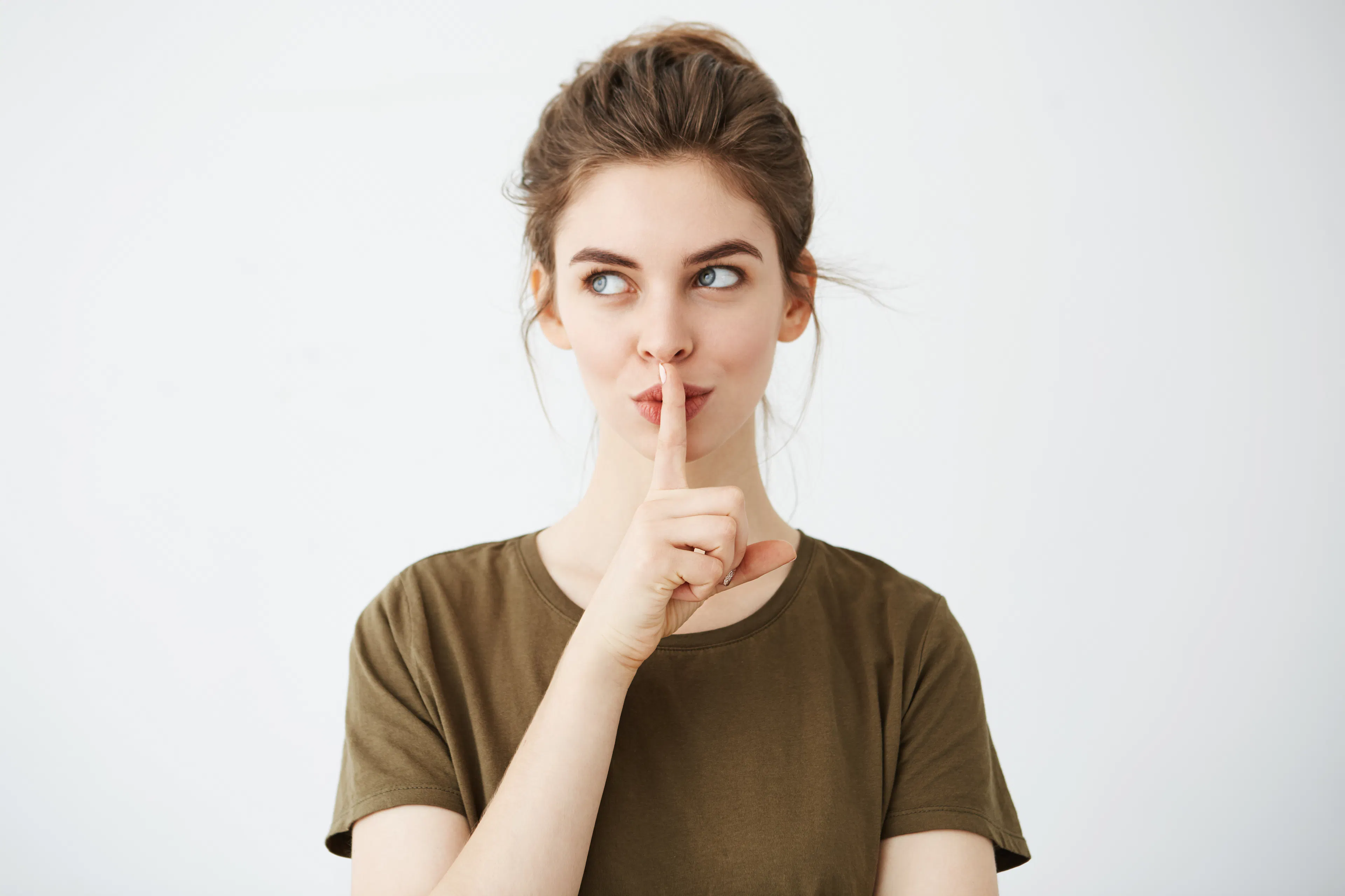 Eine weibliche Person hält den Finger vor den Mund, um eine schweigende Geste zu zeigen.