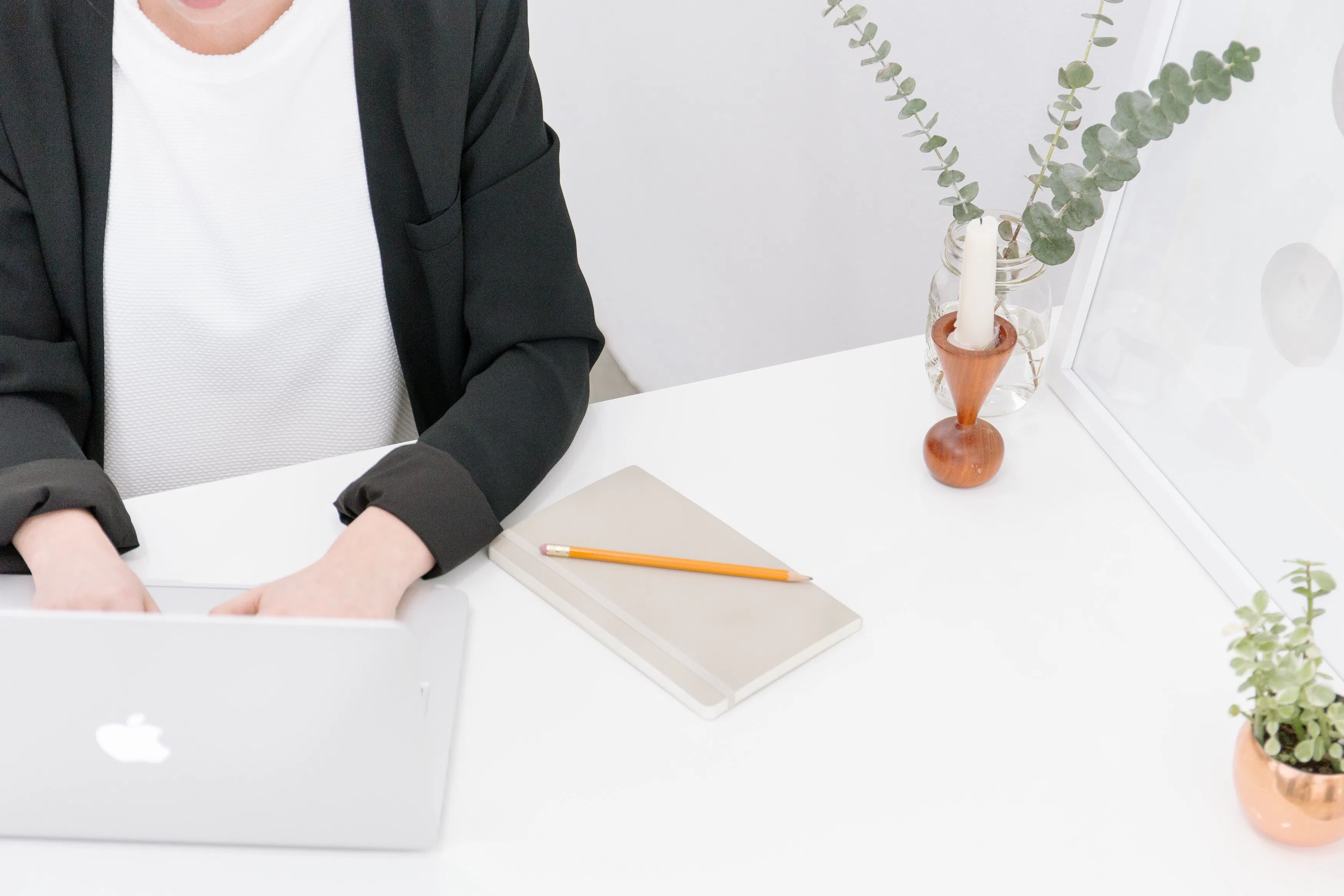 Frau sitzt am Schreibtisch und tippt in den Apple-Laptop