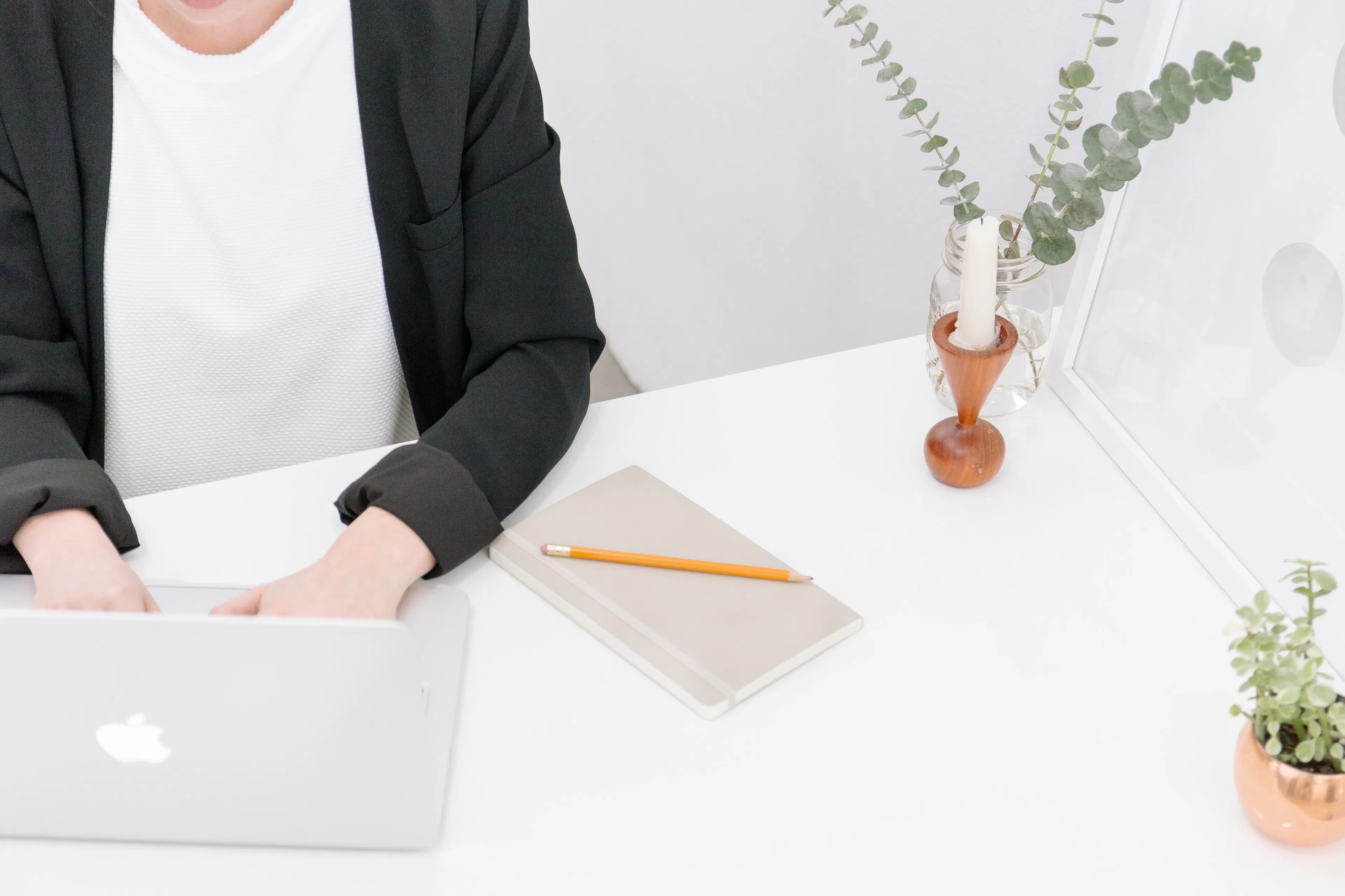 Frau sitzt am Schreibtisch und tippt in den Apple-Laptop
