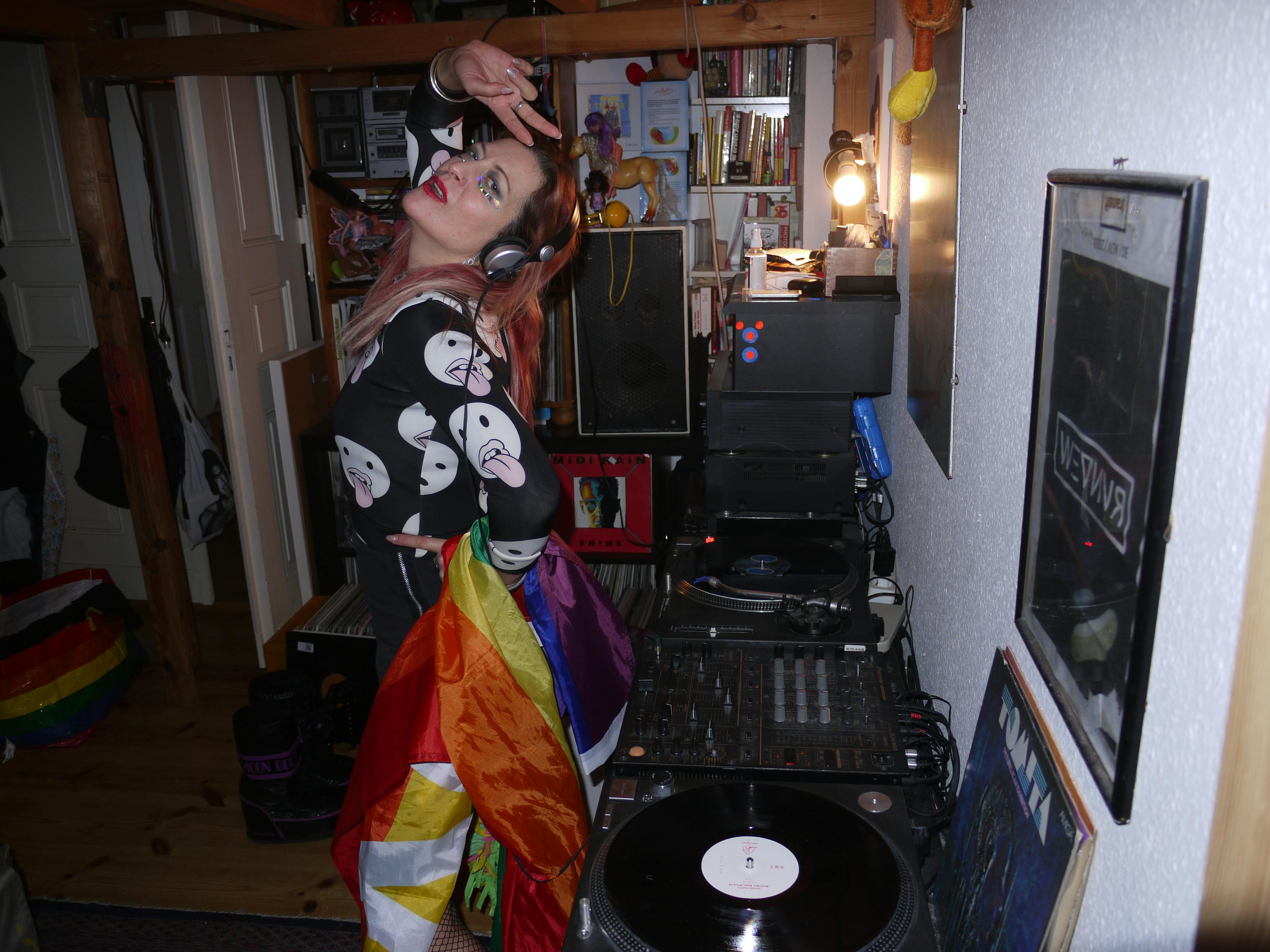 DJ Kat sharing a peace sign with pride flag and turntable