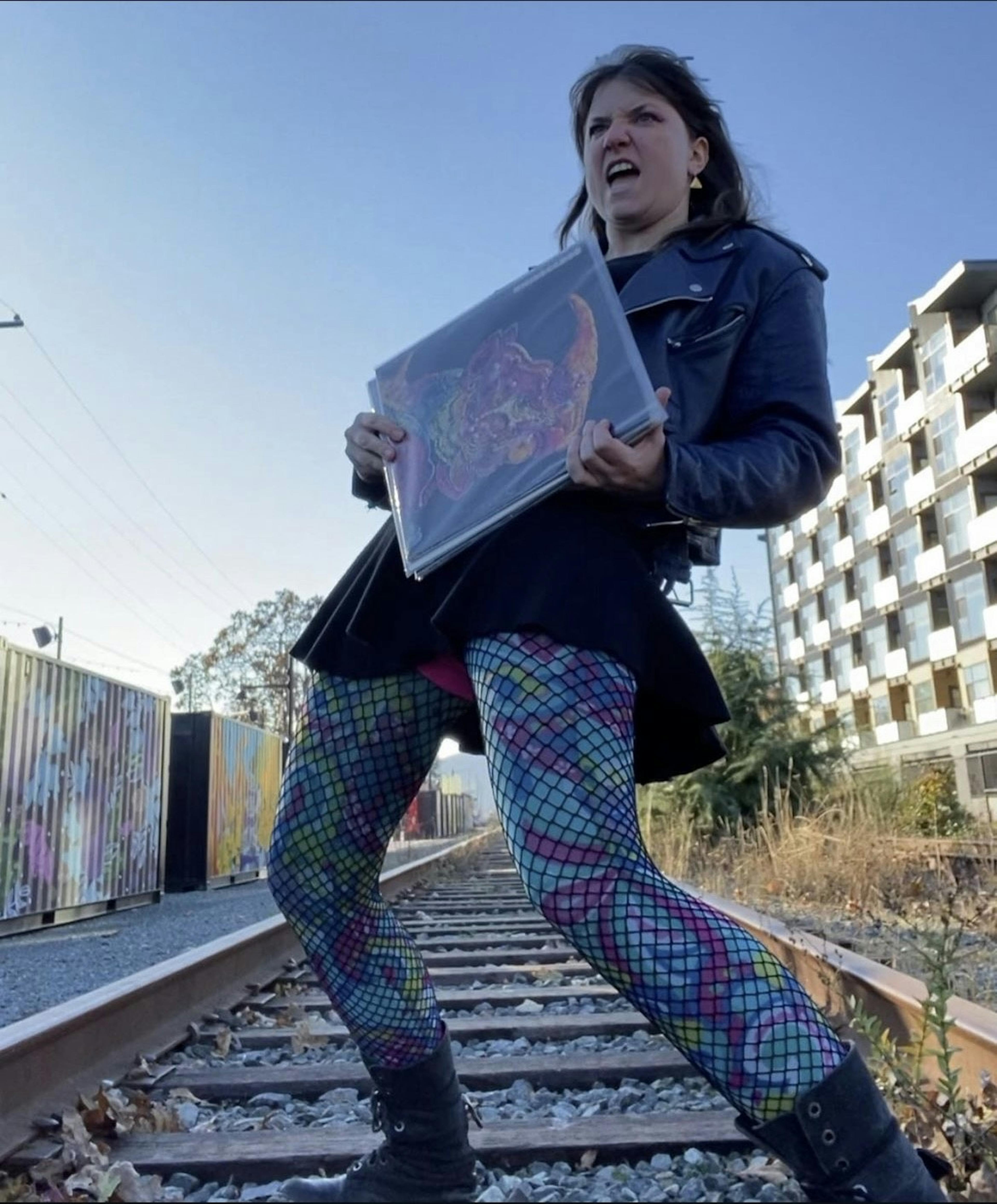 Portrait of Jenna on railroad tracks holding a record