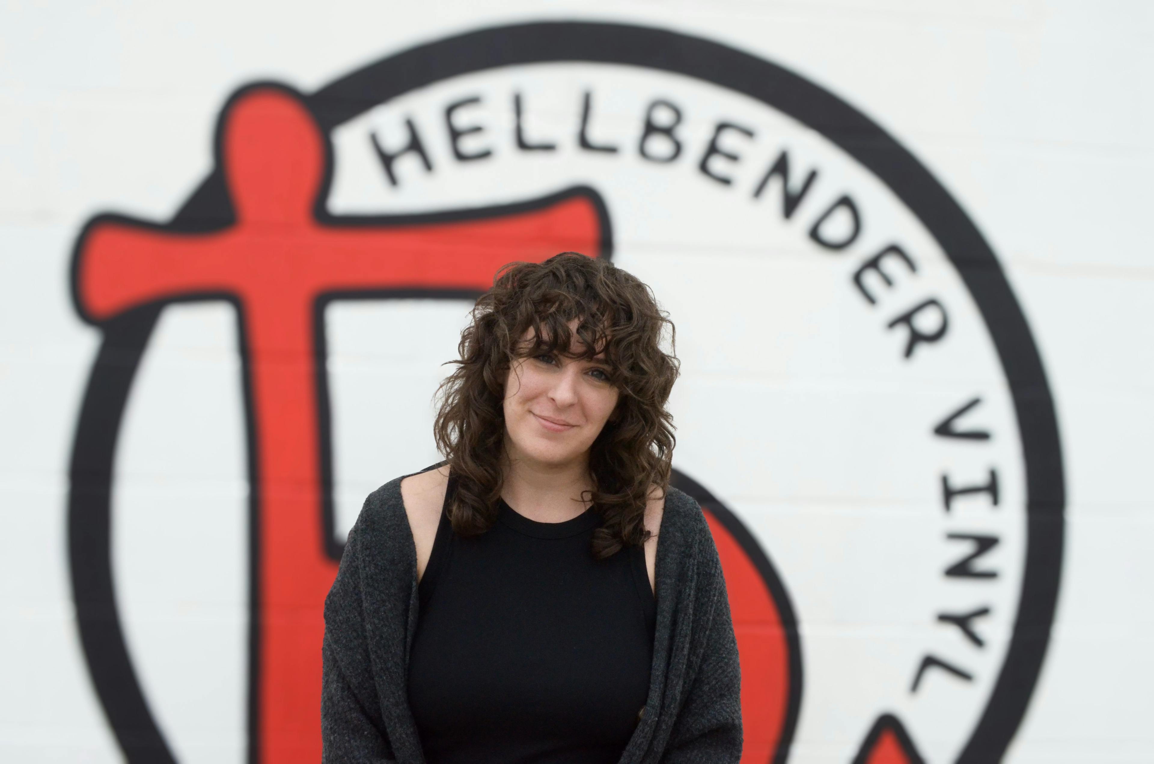 Portrait of Pam in front of Hellbender Logo
