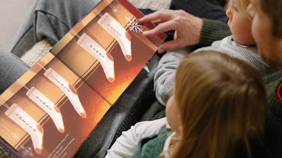 A father reading The Christmas Snowflake book for son and daughter