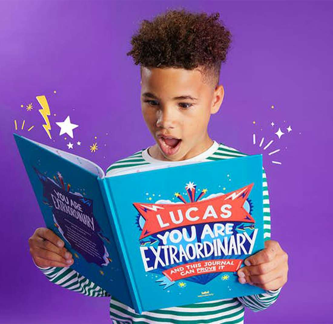 Young boy reading his personalised copy of You Are Extraordinary