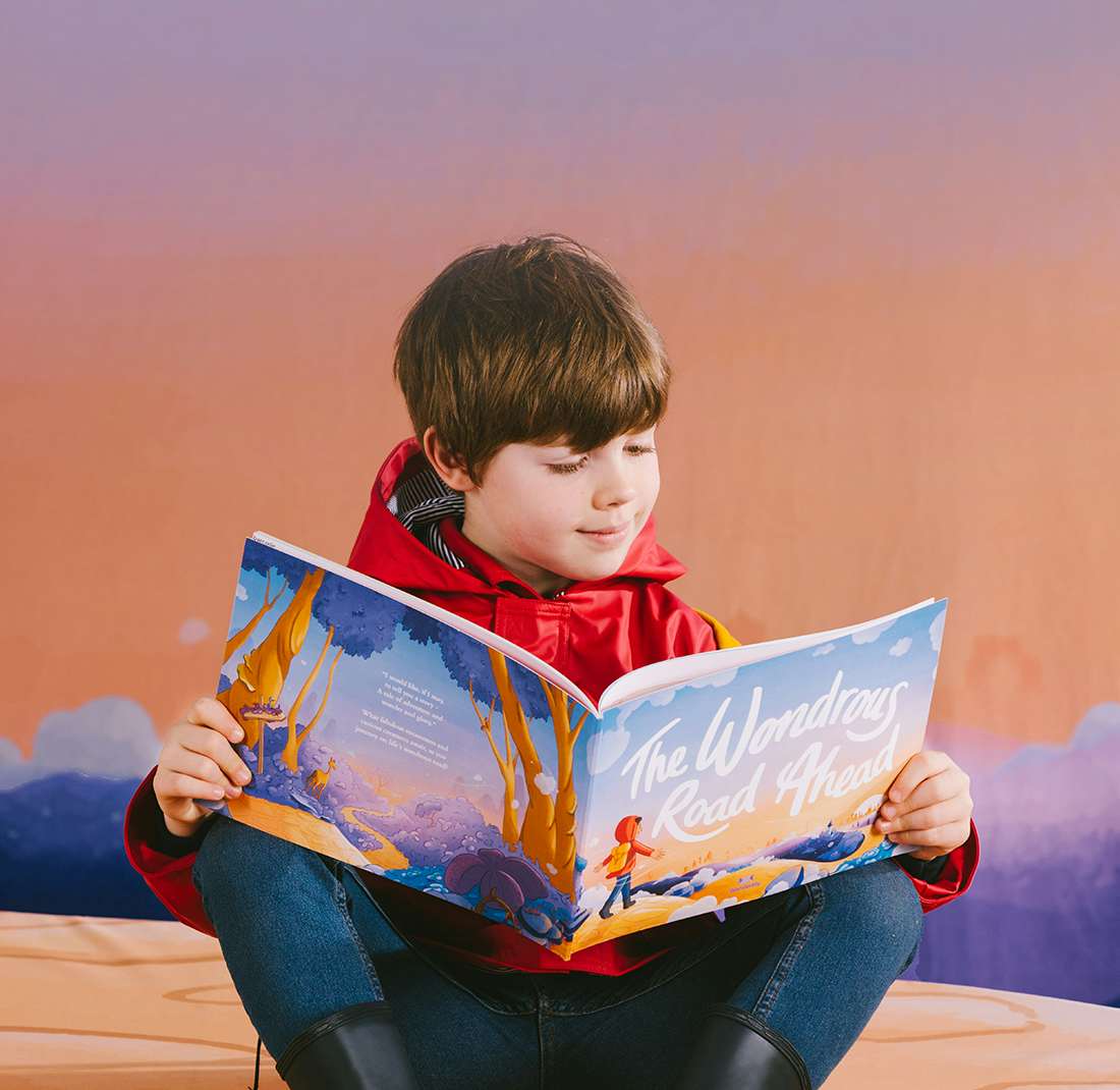Little boy reading The Wondrous Road Ahead