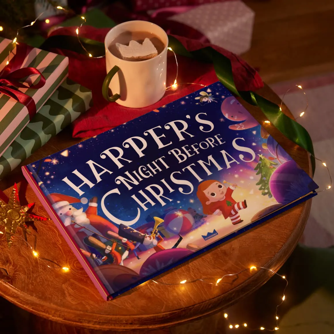 Personalised book on a table with Christmas lights and a mug