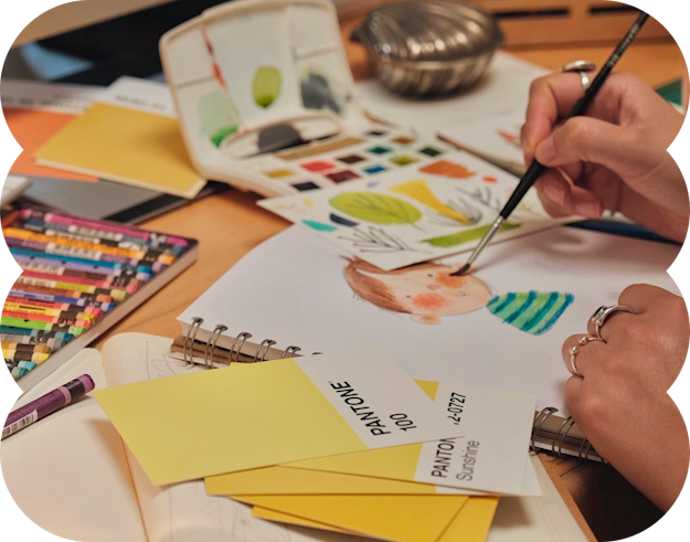 Artist painting with watercolors, surrounded by supplies.