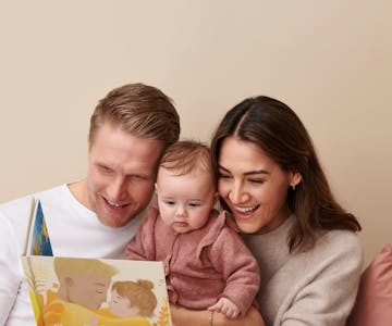 Dad, mum and baby reading personalised book