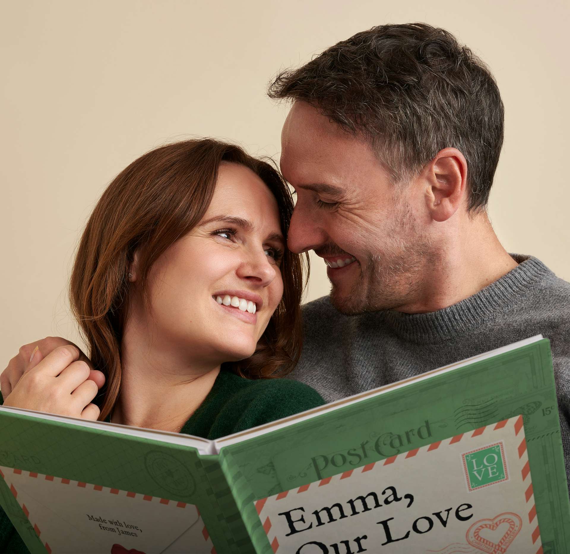 couple smiling at each other with our love story christmas book in hand