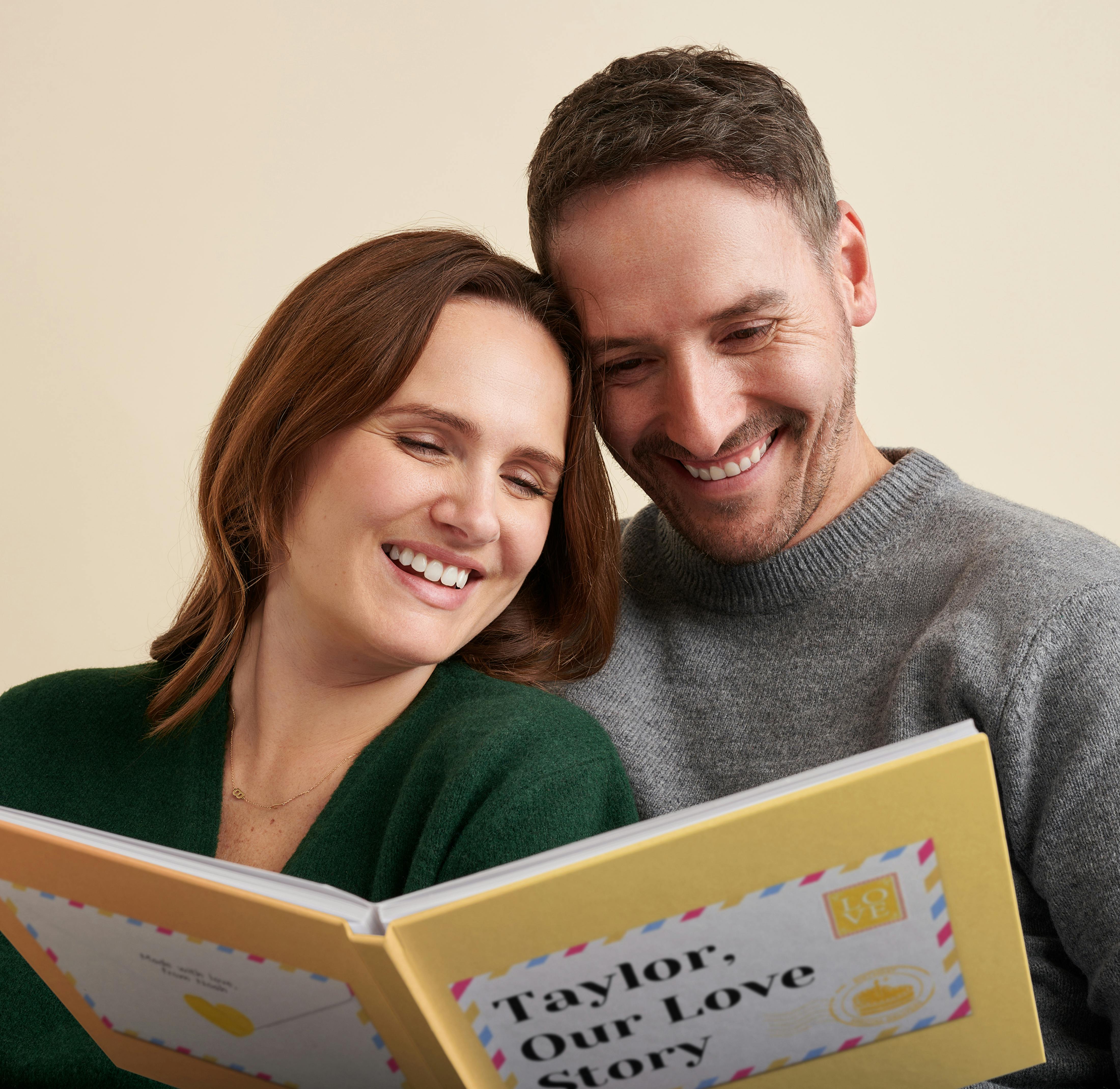 man and woman smiling reading our love story birthday edition
