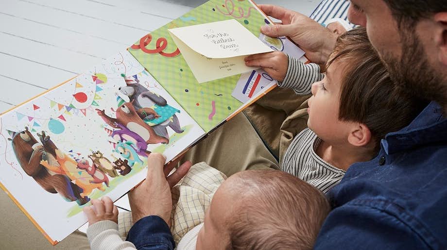 An image of the father with his two sons reading the Littlest Bear book to them