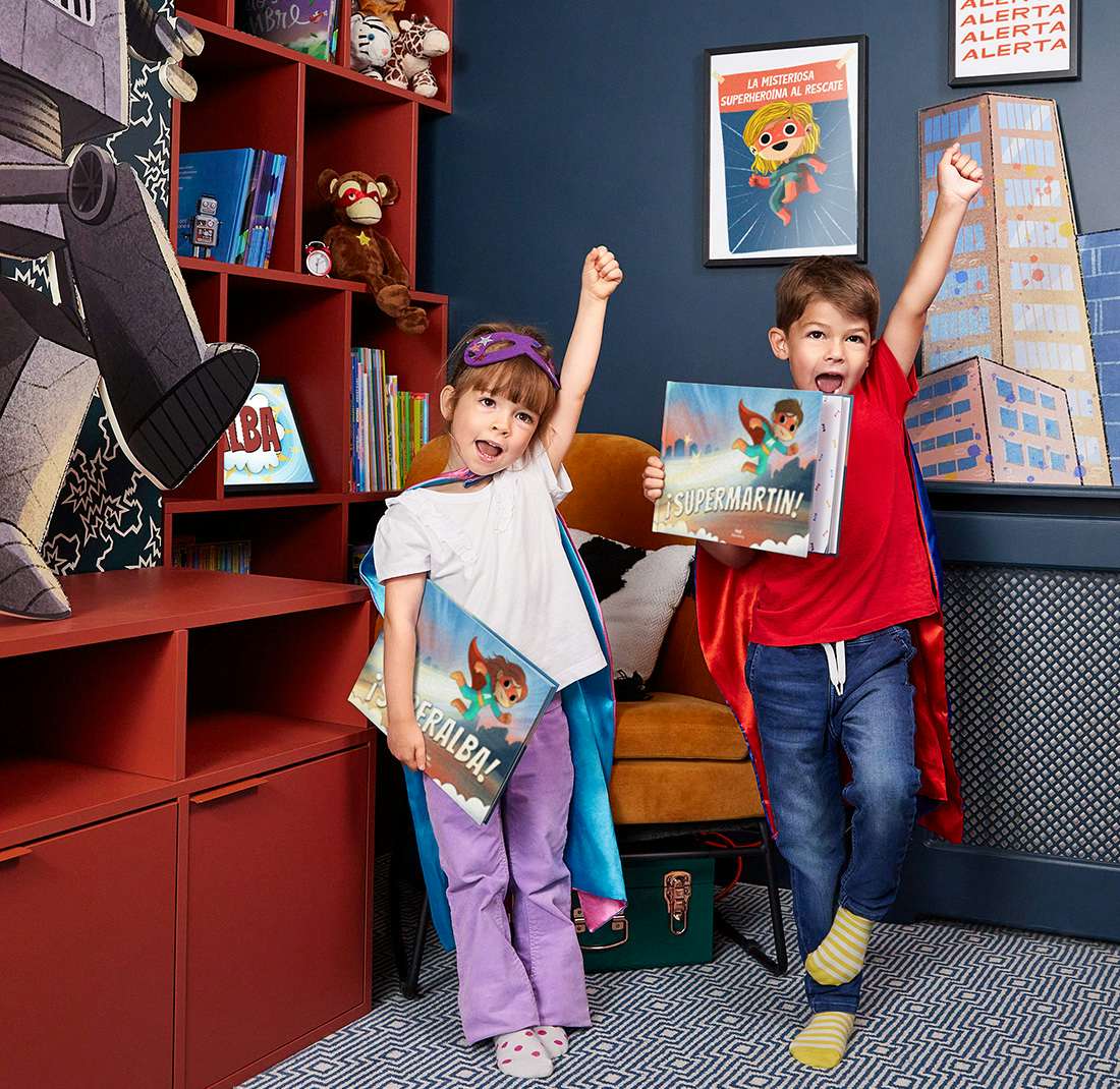  Dos niños con capas y sosteniendo sus libros.