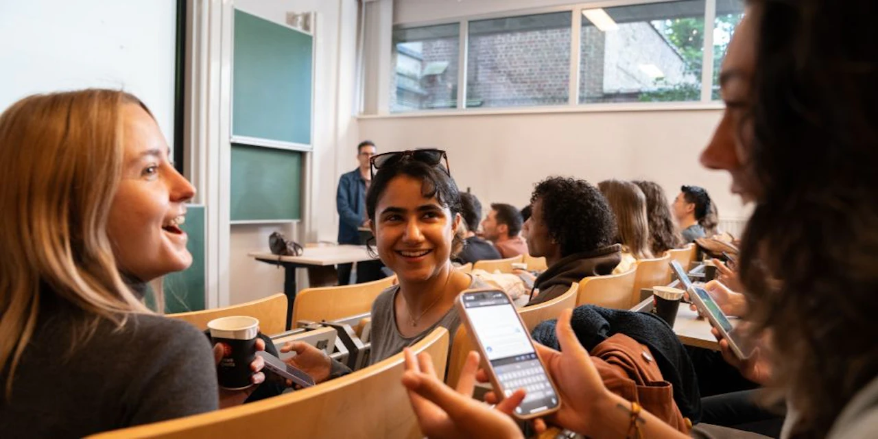 Students discussing while holding a phone in their hand.