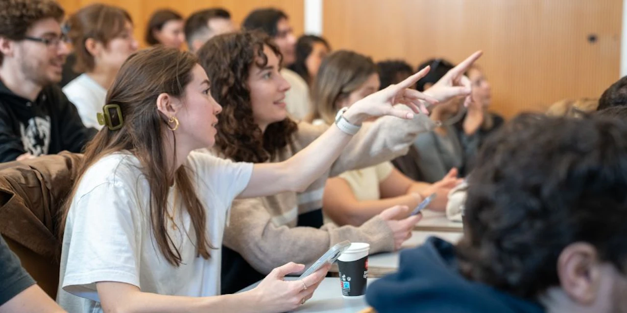 Students actively participating in a classroom, raising their hands and engaging during a lesson.