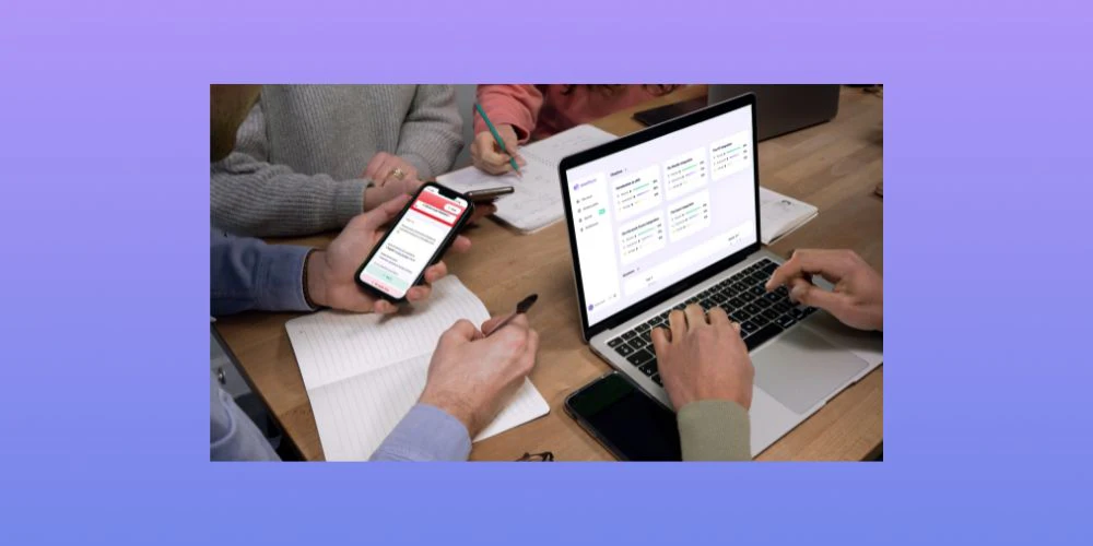 Des élèves étudient à un bureau en utilisant Wooflash sur leur téléphone et Wooclap sur leur ordinateur portable.