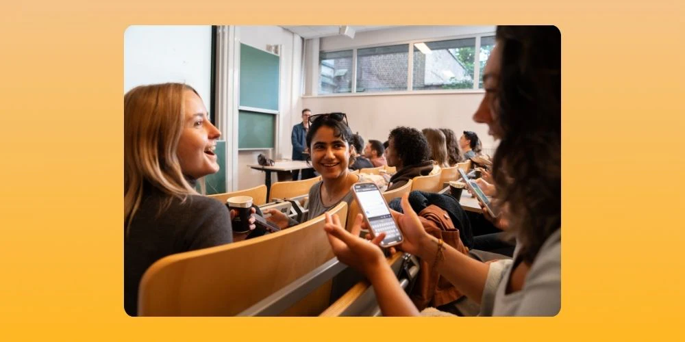 Students discussing while holding a phone in their hand.