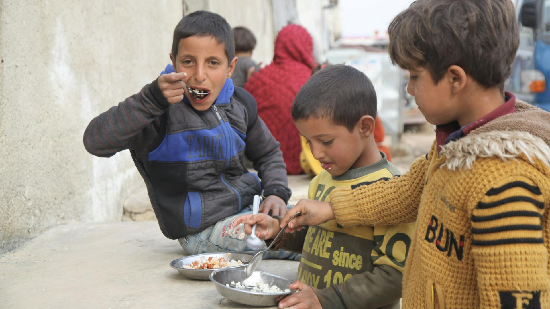 Three children in Syria eat meals provided by WCK.