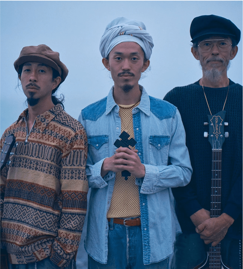 Three musicians stand together outdoors, each holding an instrument, with a serene background that evokes a sense of community and creativity.