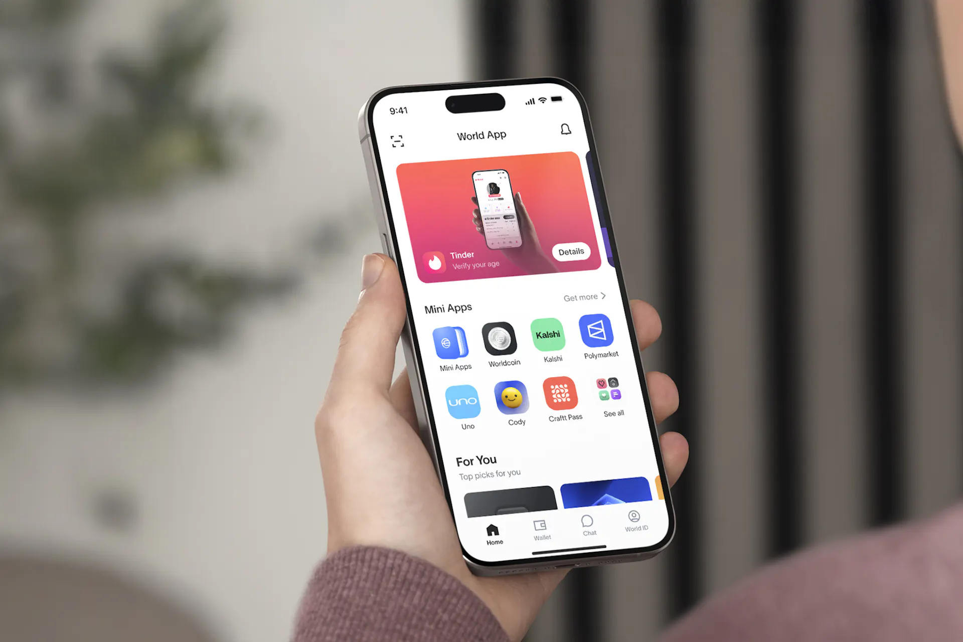 User holding a smartphone displaying the World App interface, showcasing features like secure chat and mini apps.