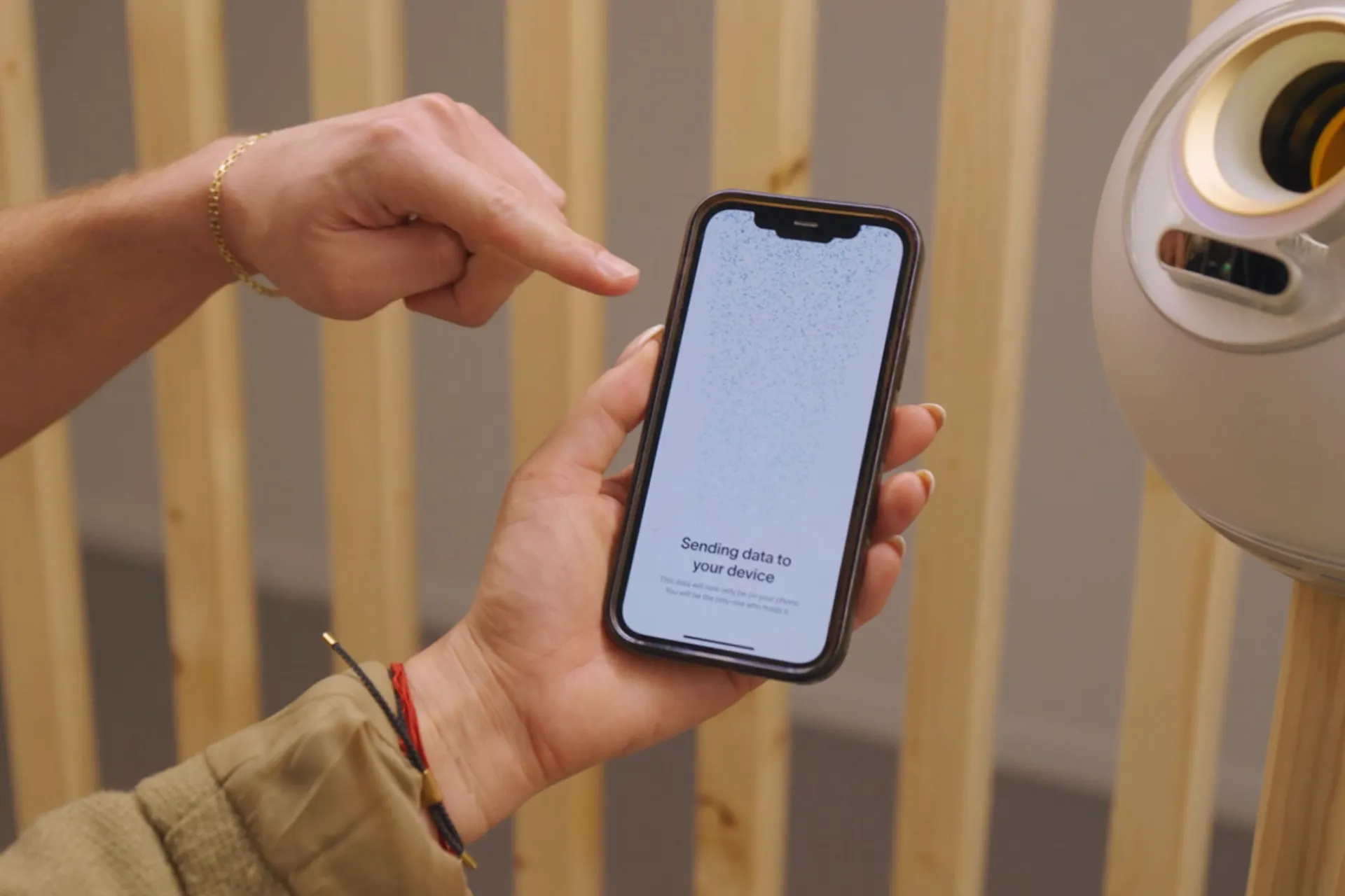 A person's hand holding a smartphone displaying a screen that says 'Sending data to your device' next to an Orb for verification.