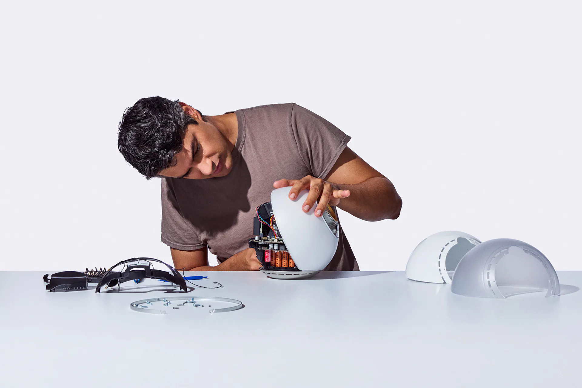 A person is assembling the Orb, focusing on its inner components, with several Orb parts on the table around them.