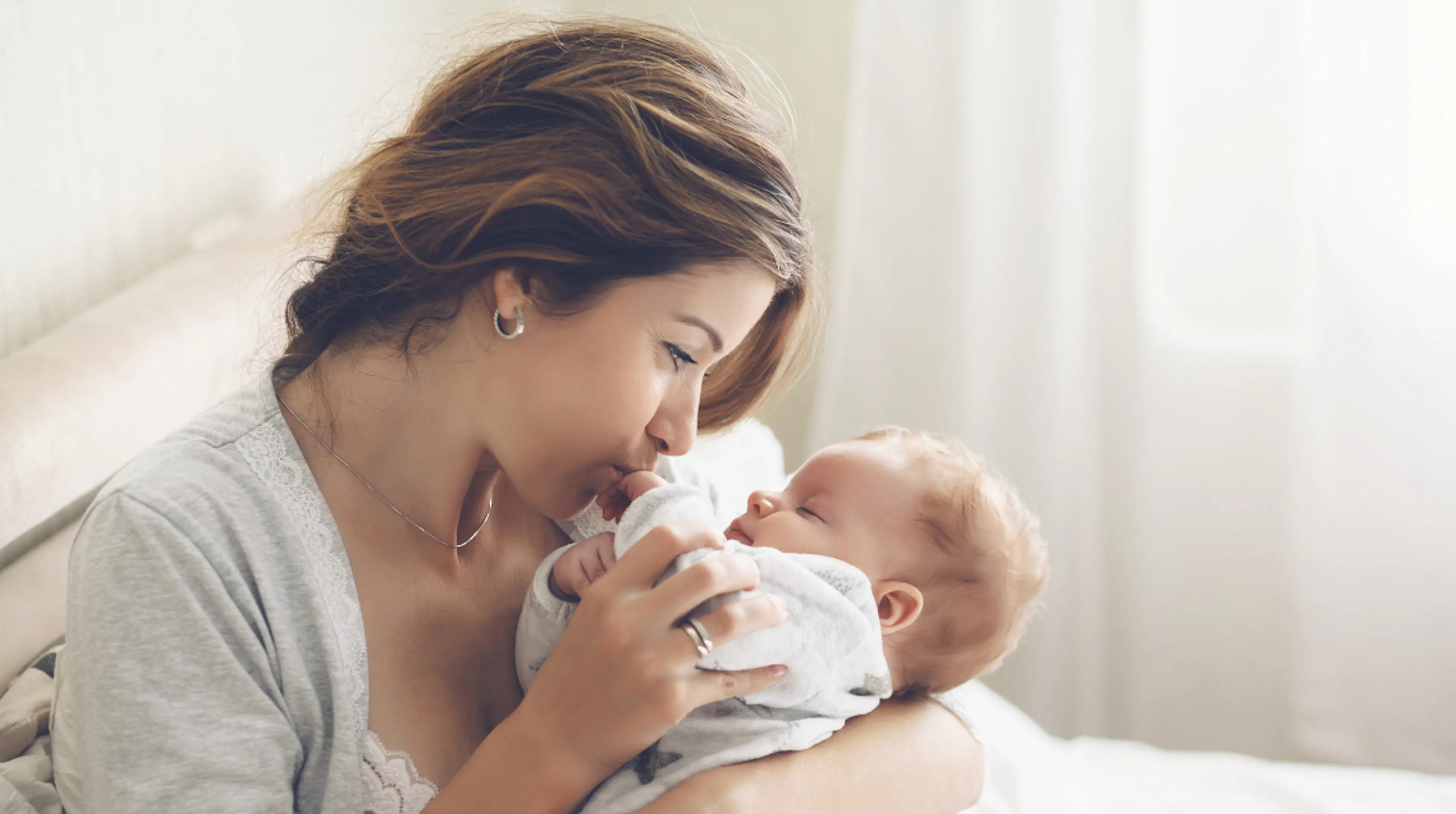 New mom holding baby representing the beautiful moments and memories to capture of baby's first year