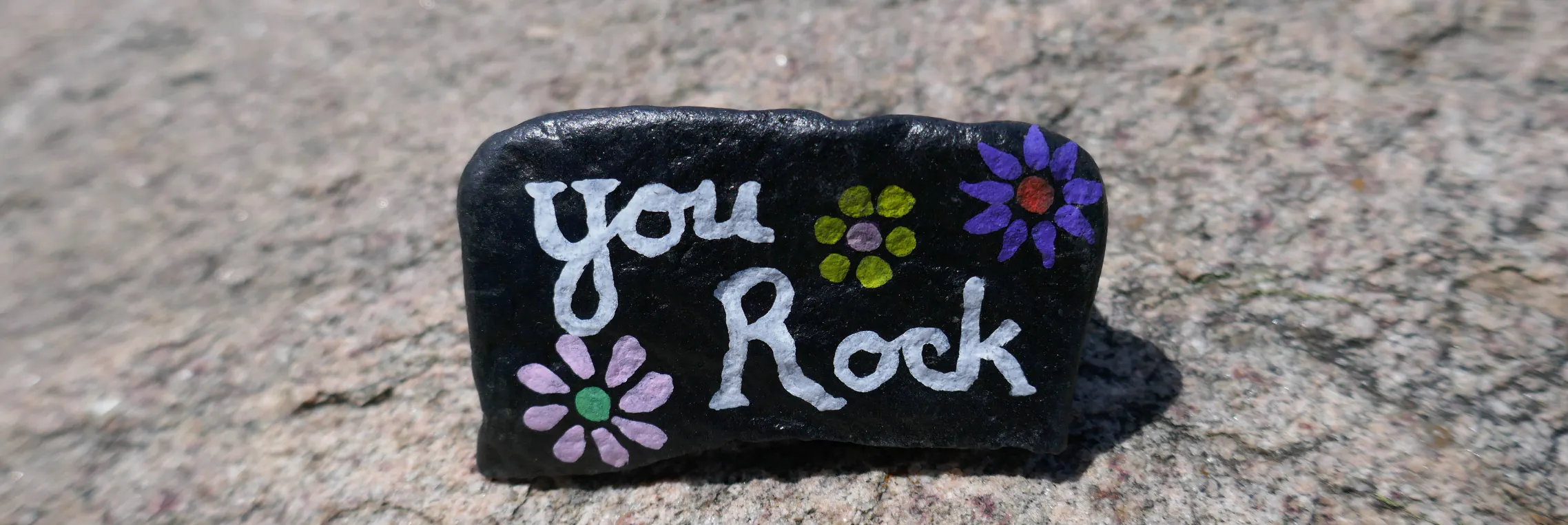 Painted kindness rock that says "you rock"
