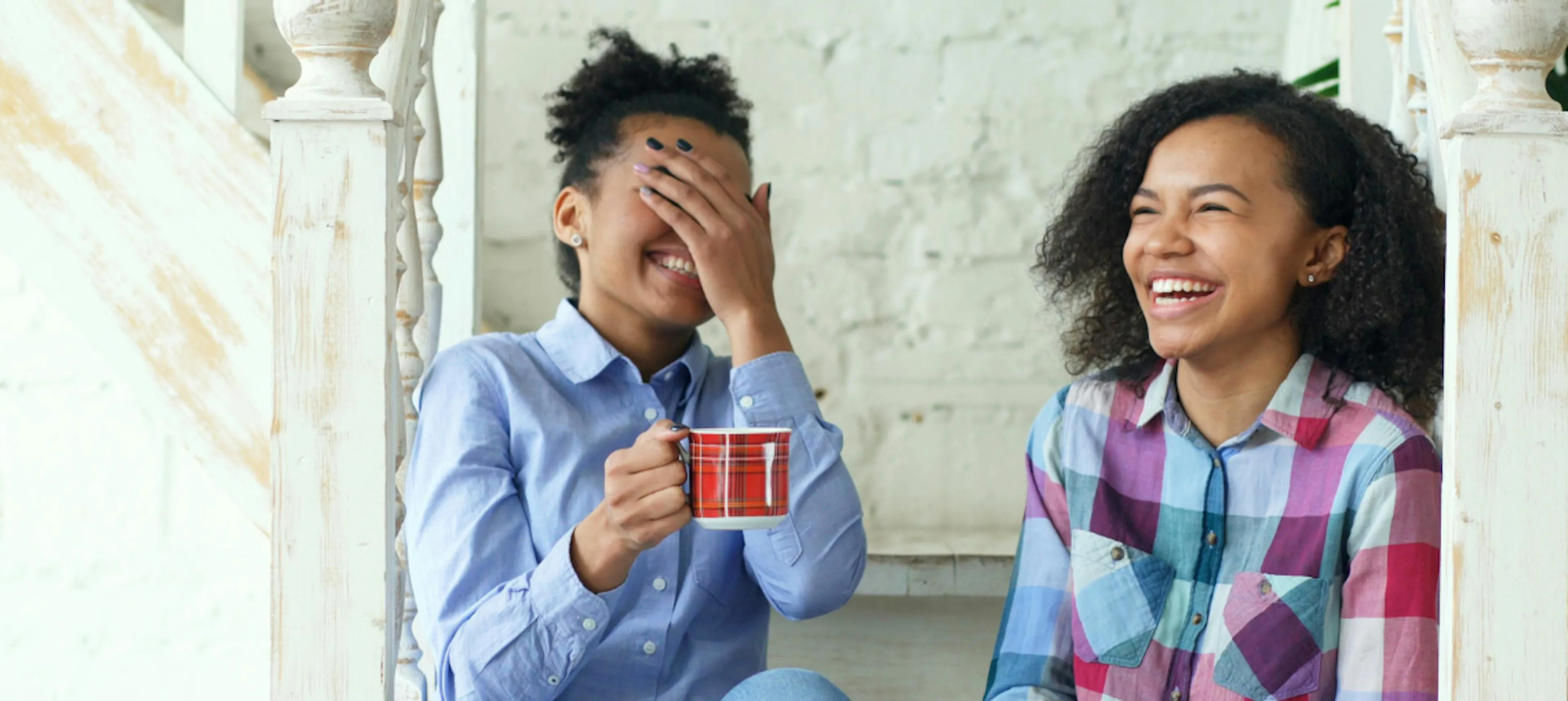 Two women laughing while having a coffee representing a friendship check-in