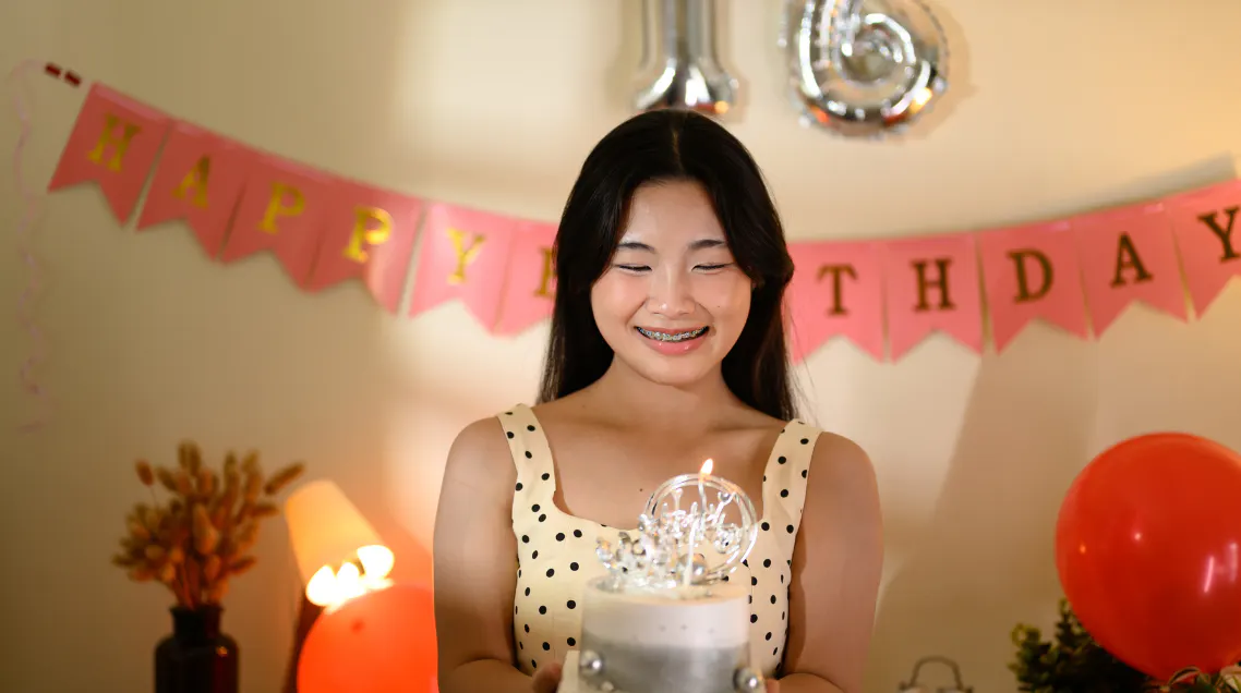 Young girl smiling and holding a sweet 16 birthday cake