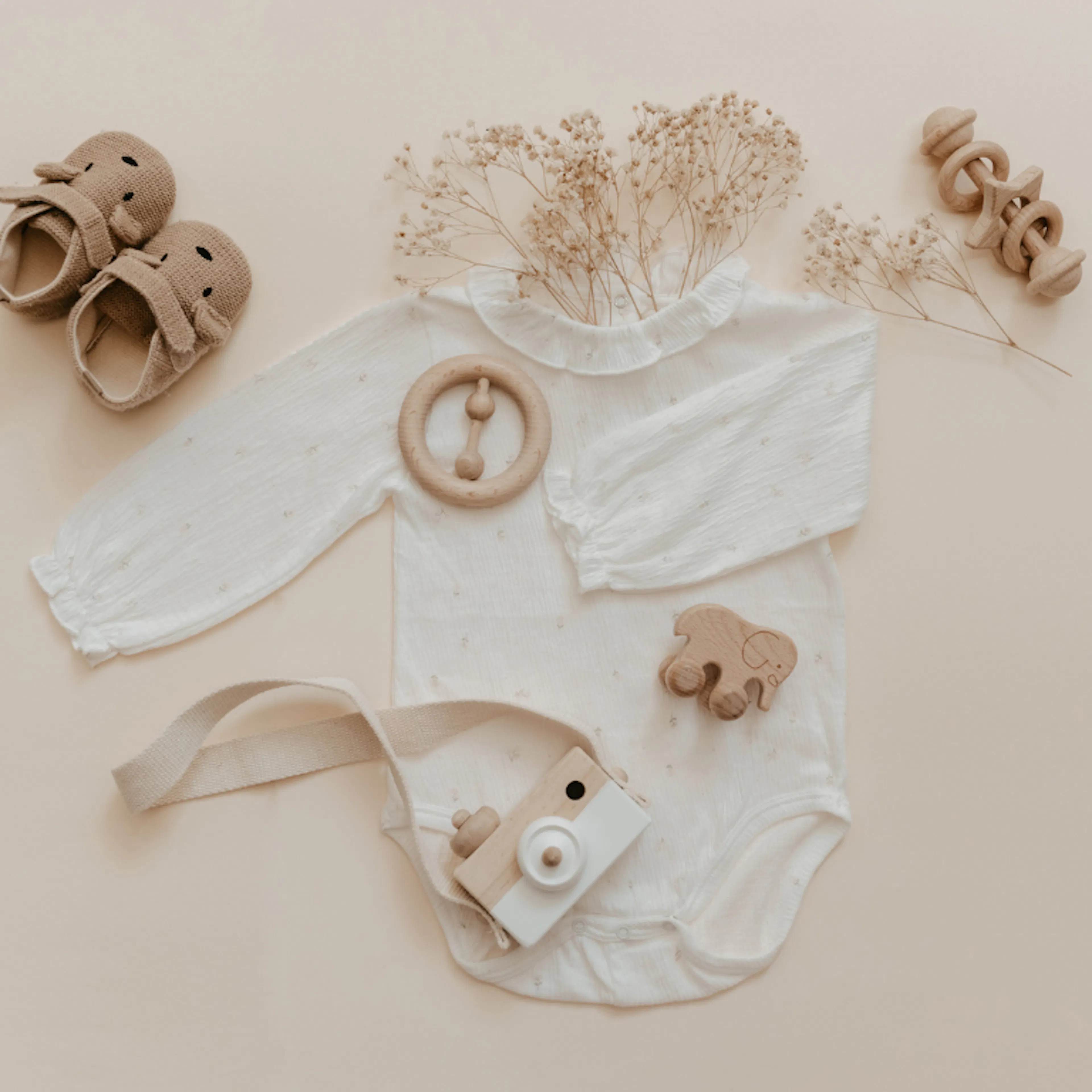 Baby's first year keepsake items including tiny shoes, rattle, and plush toy arranged as a time capsule