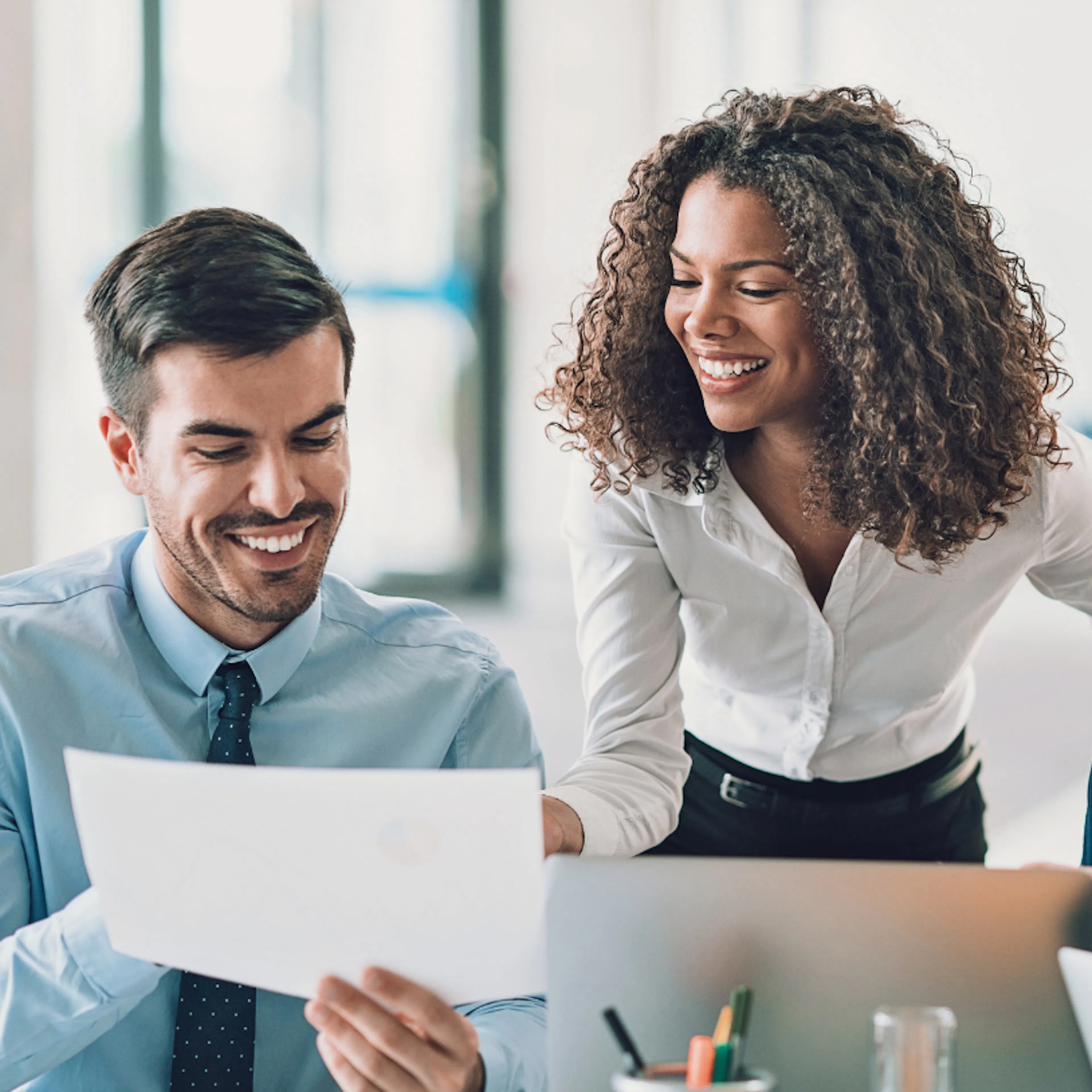 Employee smiling while she speaks with colleagues, representing what it feels like to work somewhere that notices you